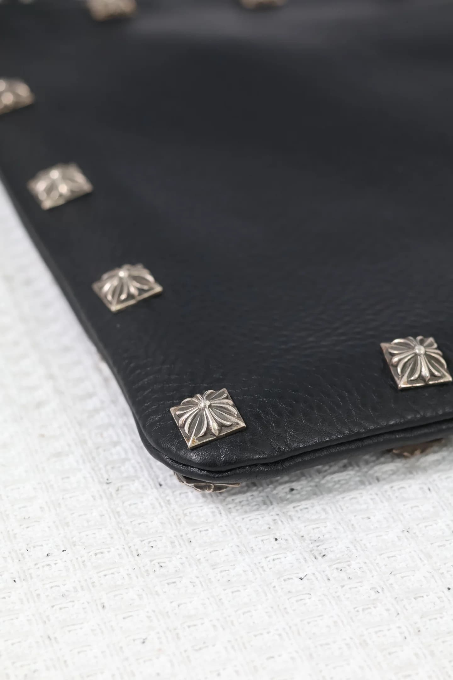 Деталь нижнего угла кожаного клатча Chrome Hearts с заклепками