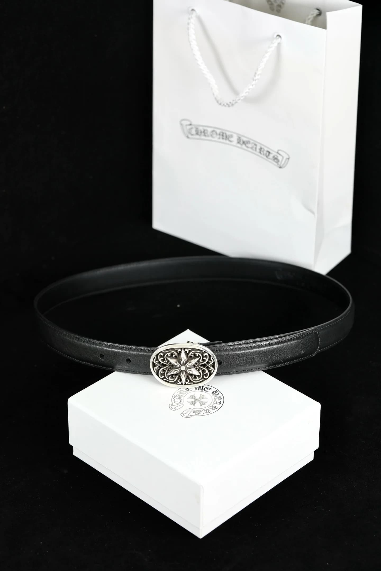 Черный кожаный ремень Chrome Hearts с серебряной пряжкой на фоне фирменной упаковки