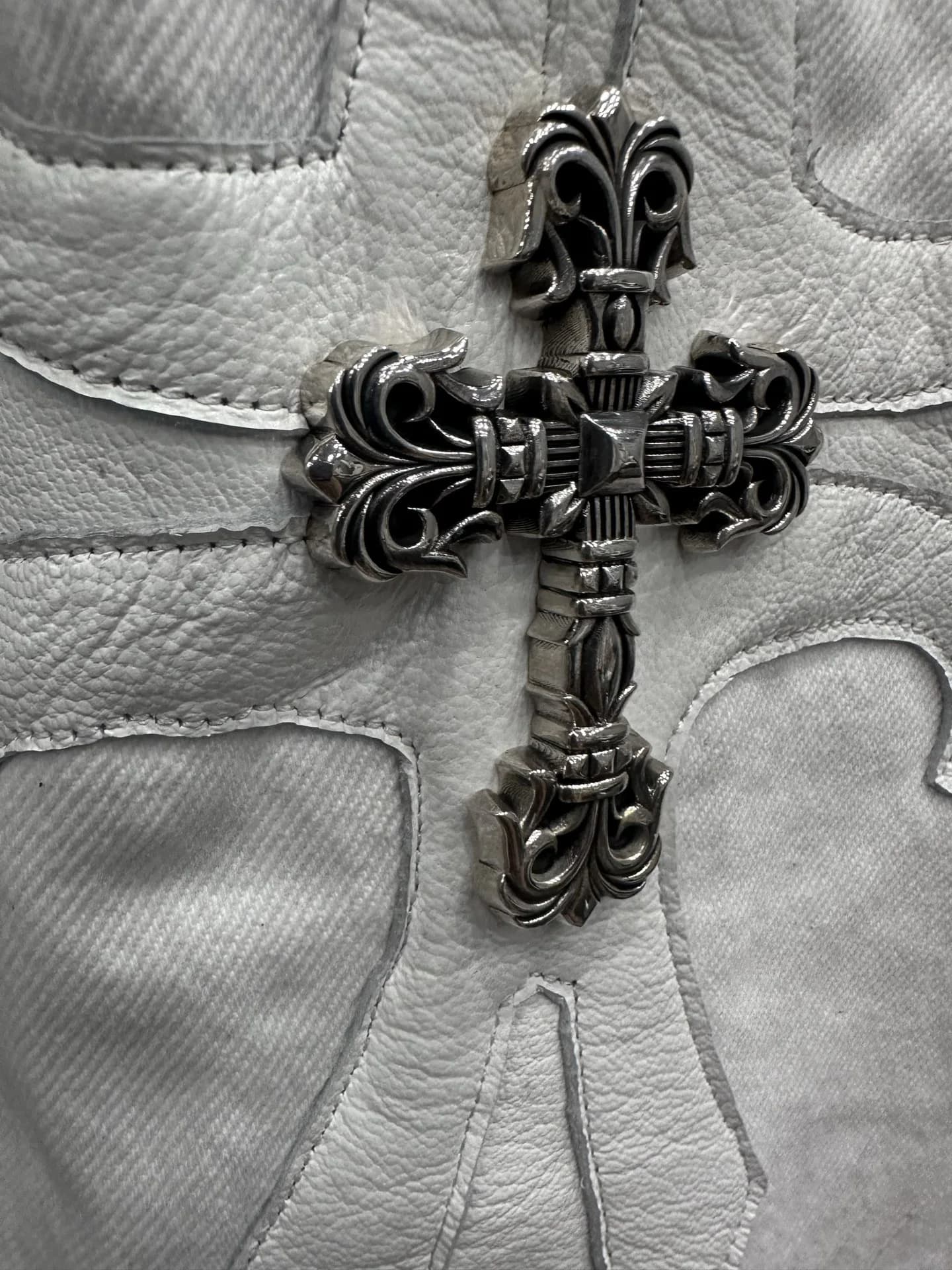 Крупный план серебряного креста Chrome Hearts на кожаной нашивке