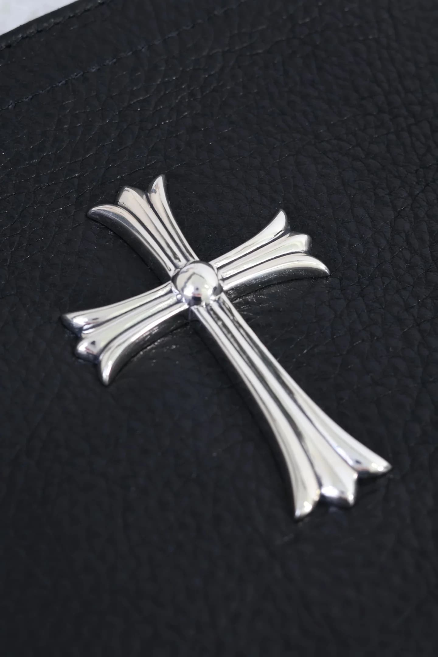 Крупный план серебряной накладки в виде креста CH Cross