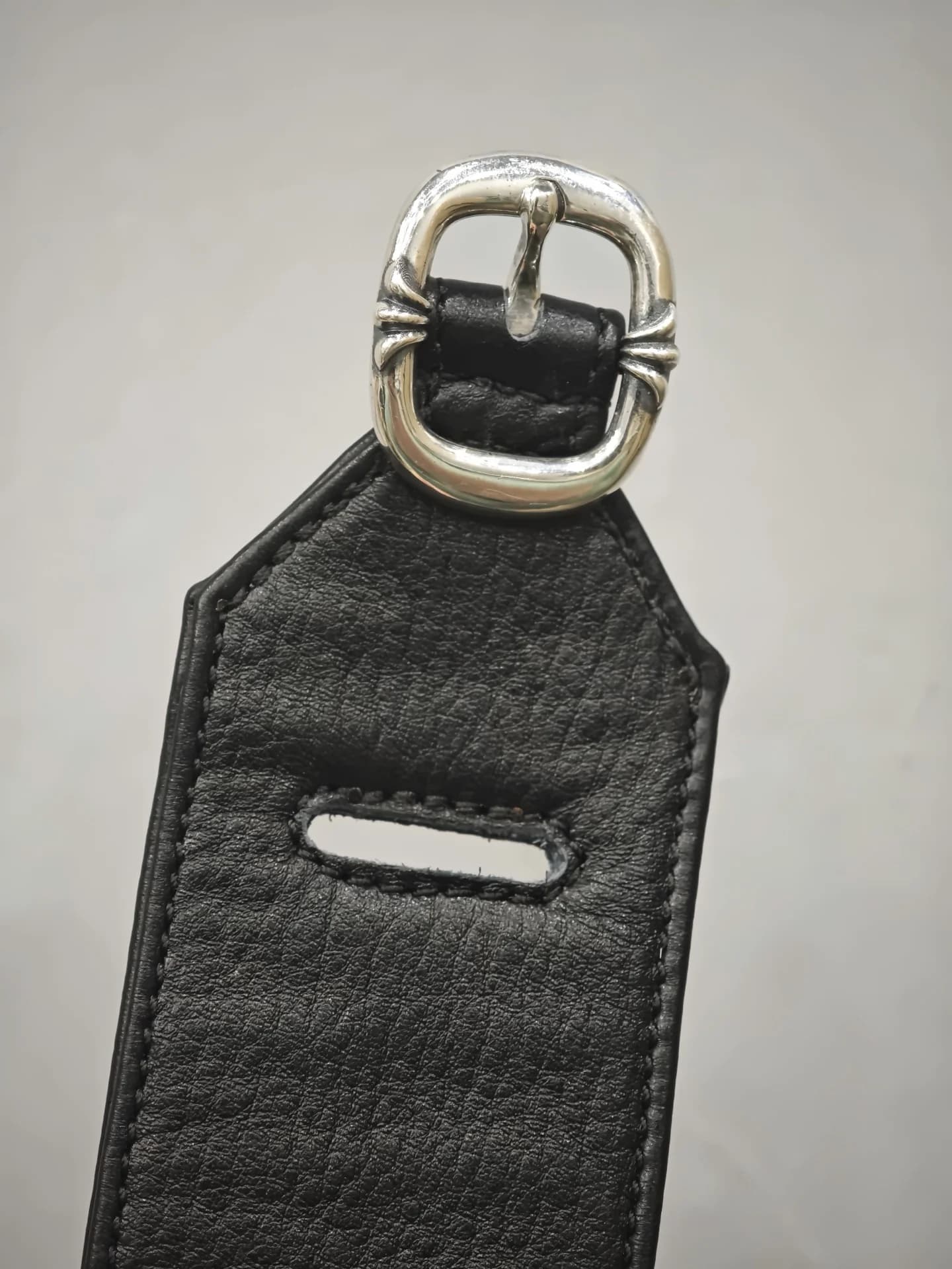 Крепление серебряной пряжки и прорезь на широком кожаном ремне Chrome Hearts