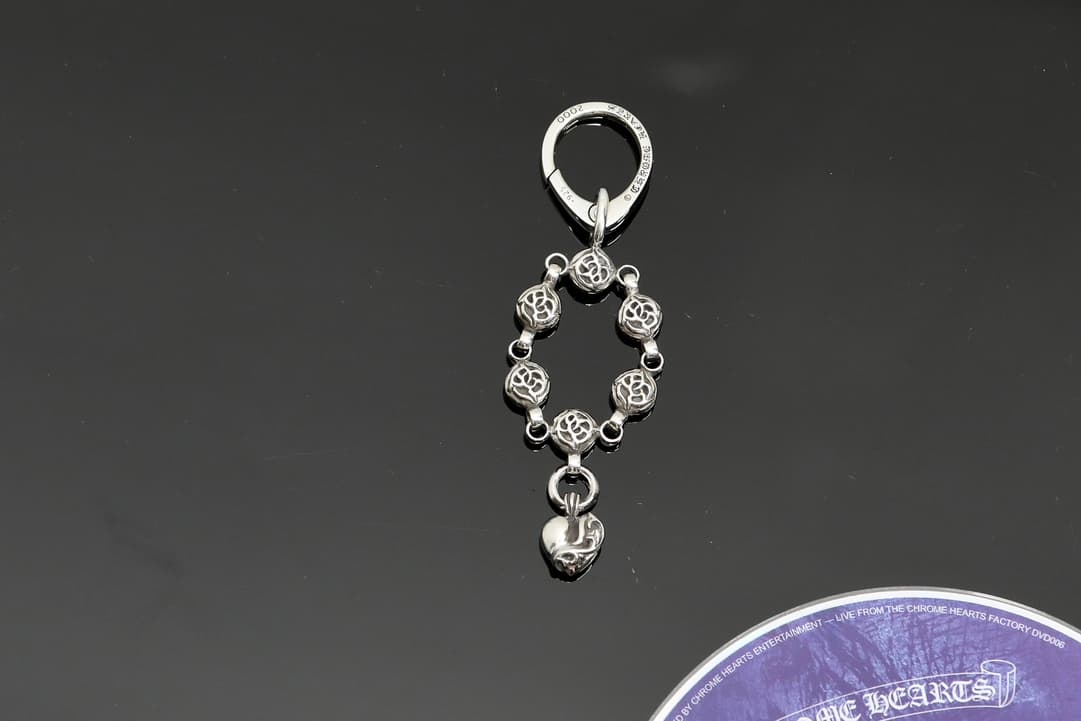 Серебряный кулон для сумки Chrome Hearts с резными бусинами и подвеской в виде сердца на темном фоне