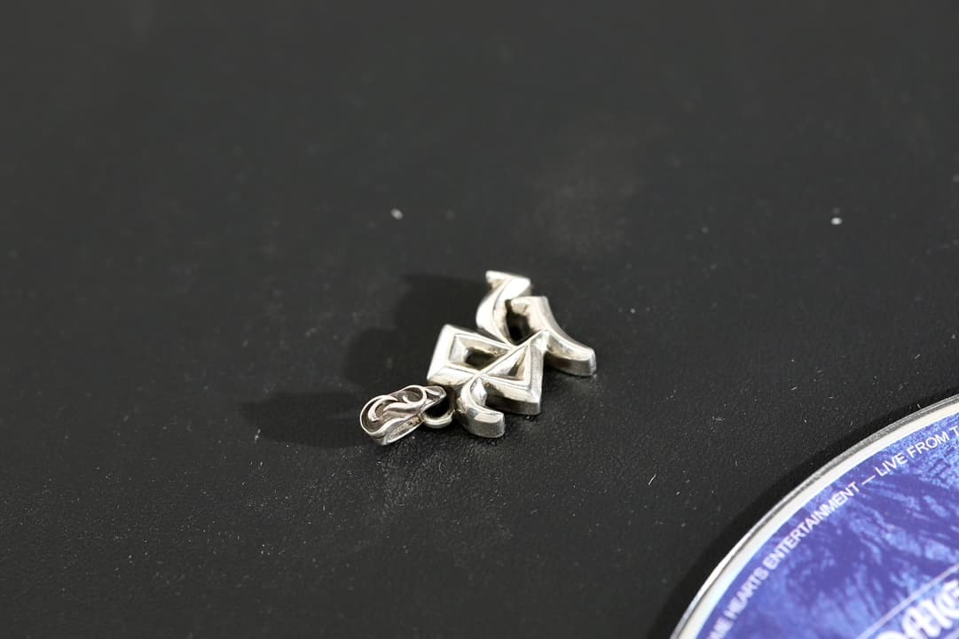 Вид сбоку на рельефную серебряную подвеску Chrome Hearts R