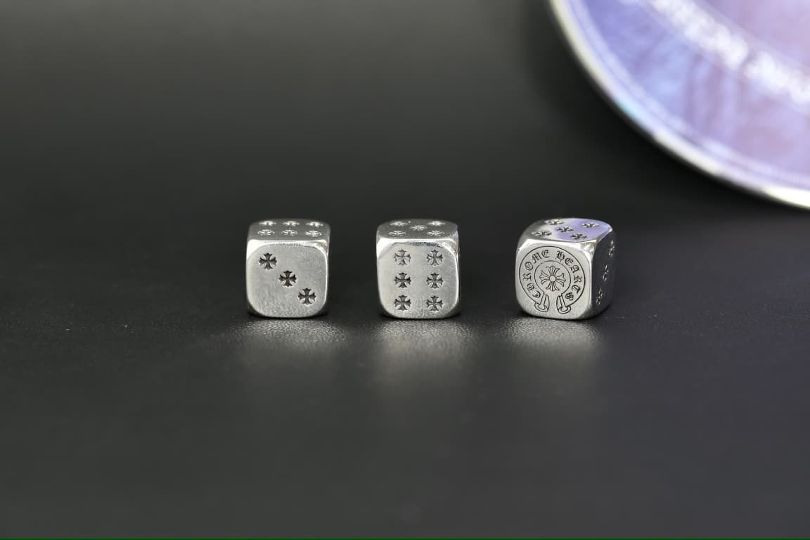 Серебряные игральные кубики Chrome Hearts в ряд на темном фоне