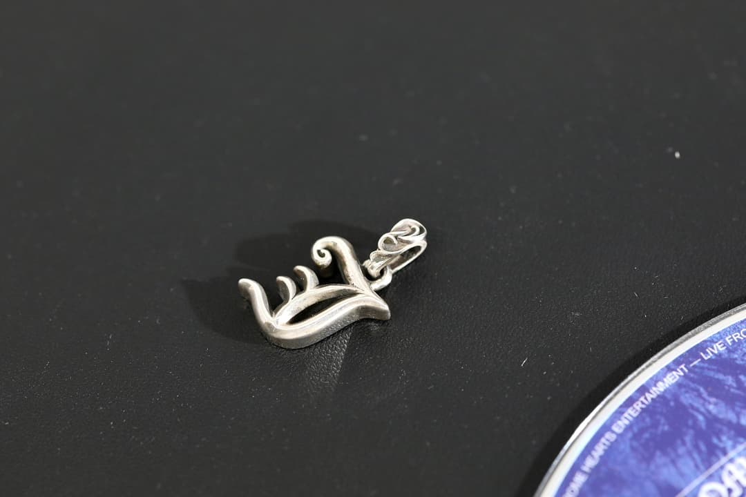 Подвеска Chrome Hearts буква J под углом на темном фоне