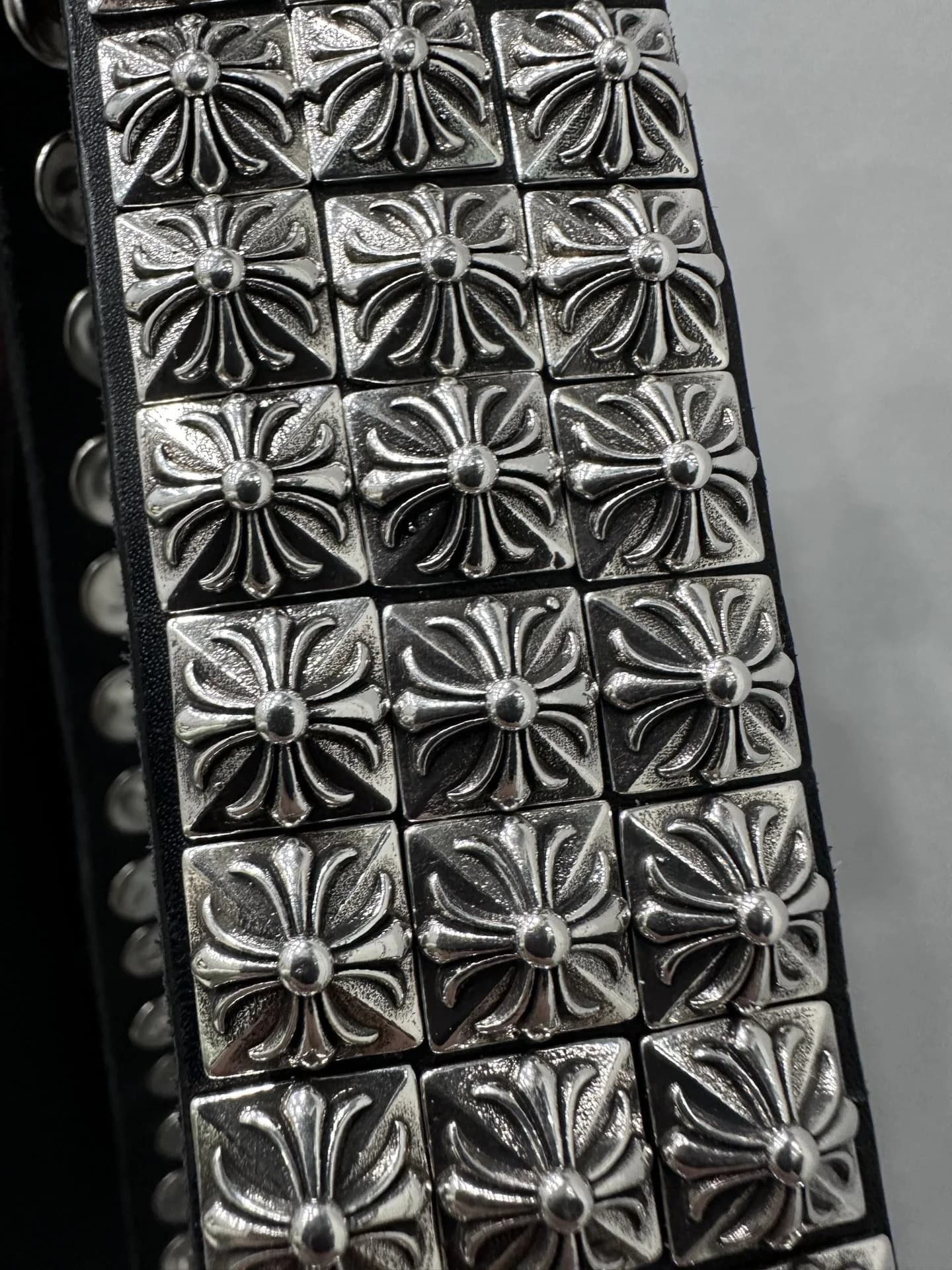 Крупный план квадратных серебряных заклепок Chrome Hearts с рельефным крестом