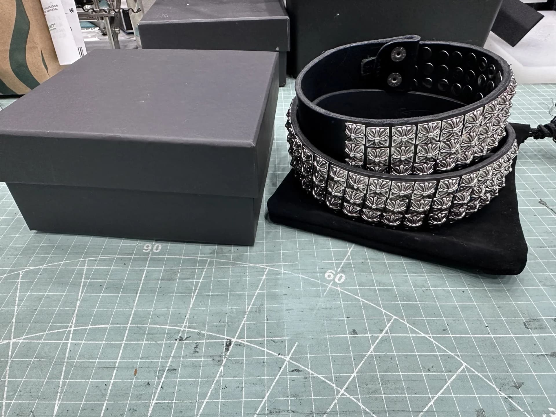 Черный ремень с заклепками Chrome Hearts рядом с фирменной коробкой и чехлом