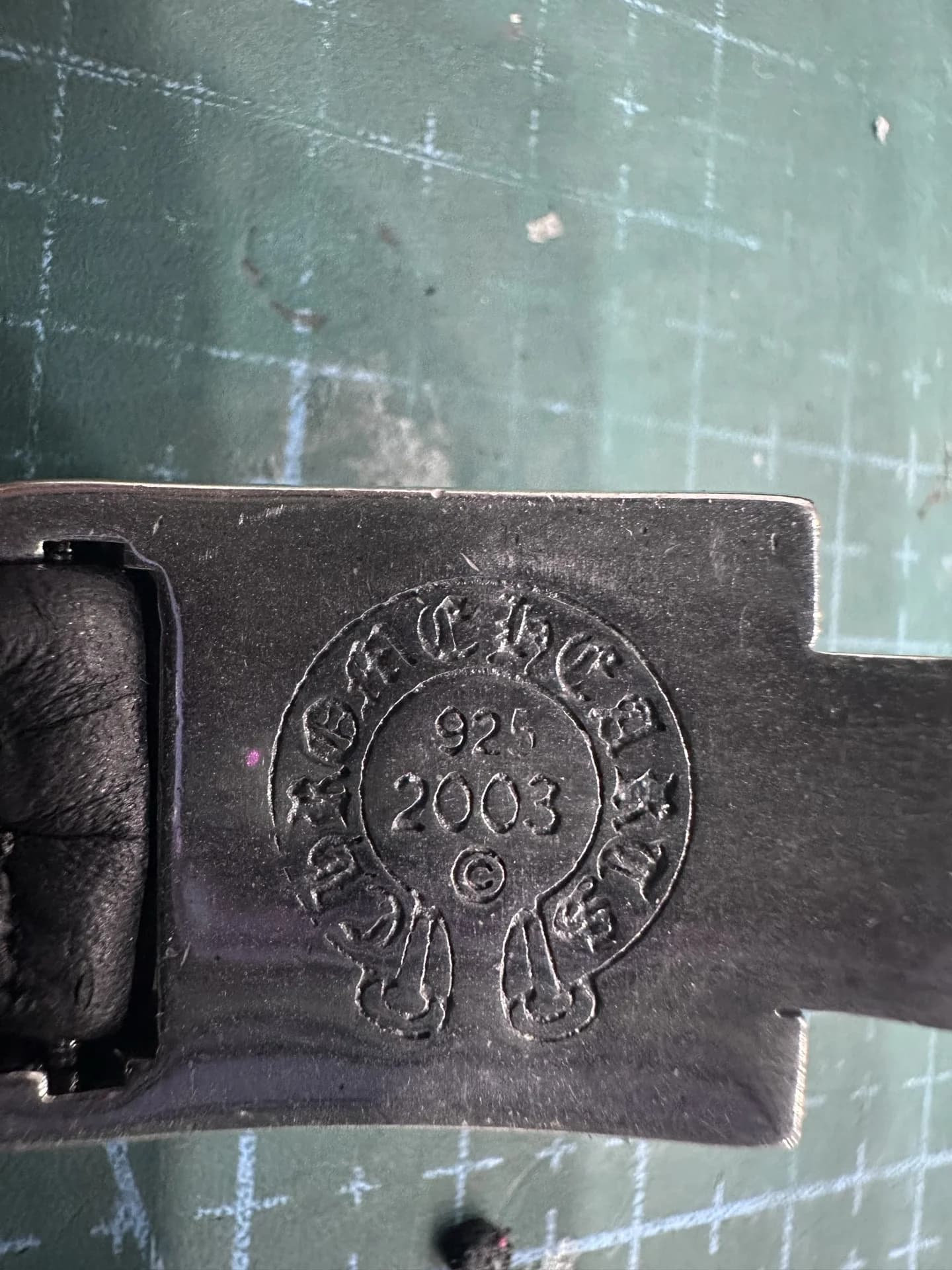 Крупный план гравировки Chrome Hearts 925 на обратной стороне серебряной застежки