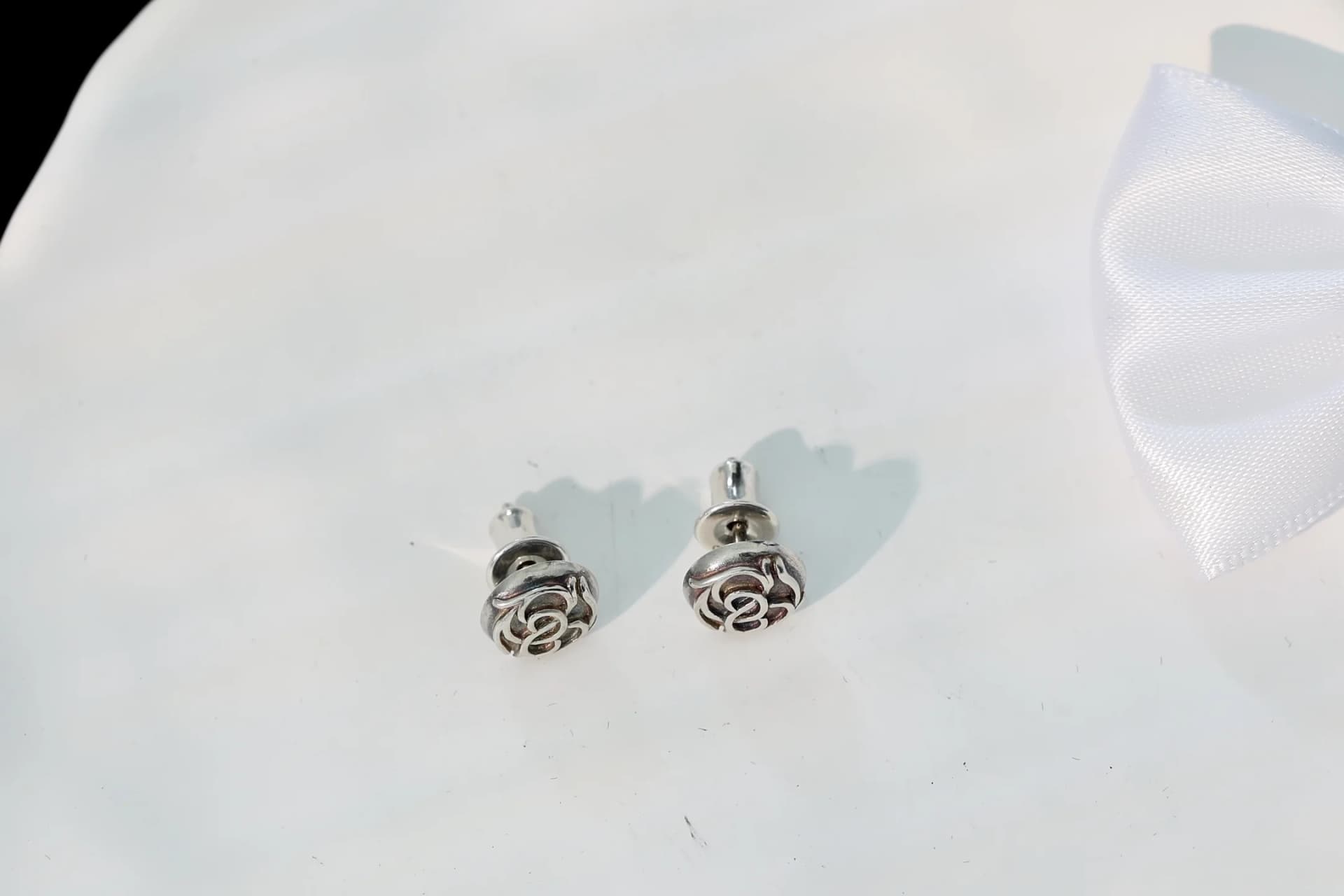 Пара серег Chrome Hearts с застежками на белом фоне