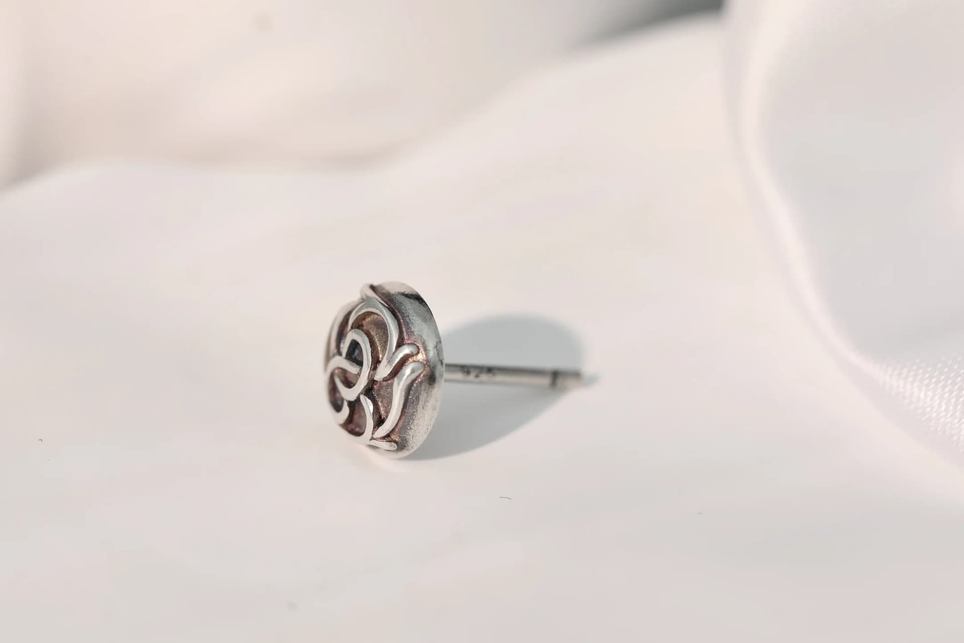 Серьга-гвоздик Chrome Hearts в профиль на белой ткани