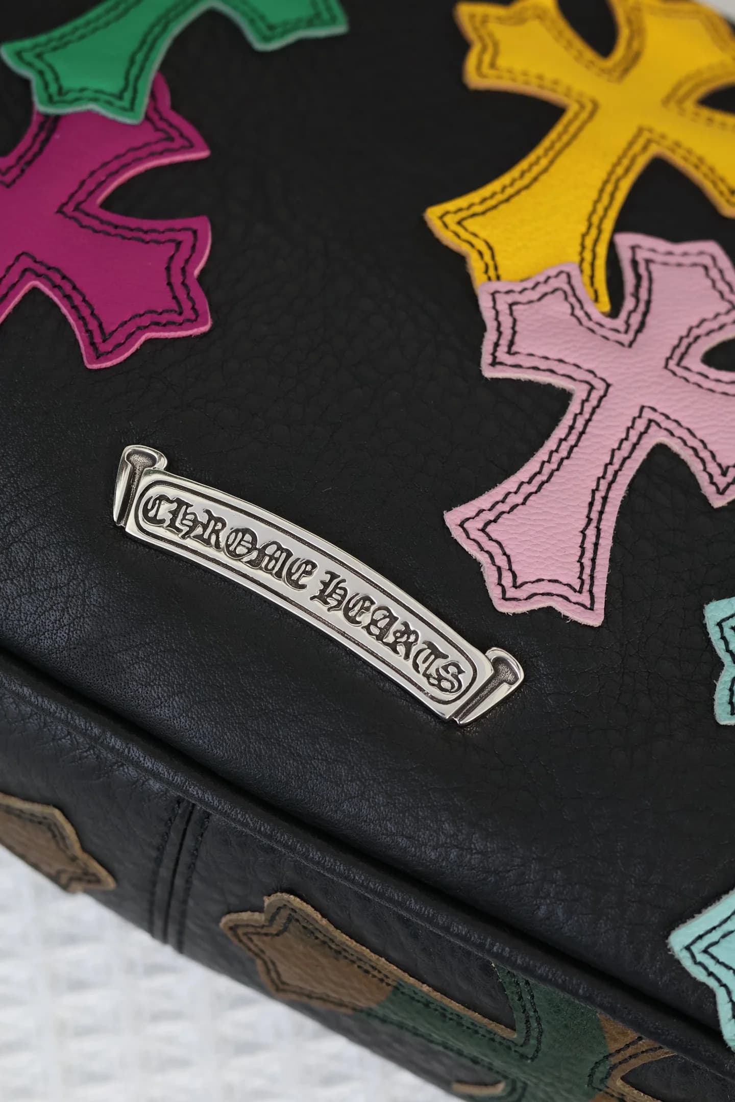 Крупный план металлической планки с гравировкой Chrome Hearts и кожаных нашивок