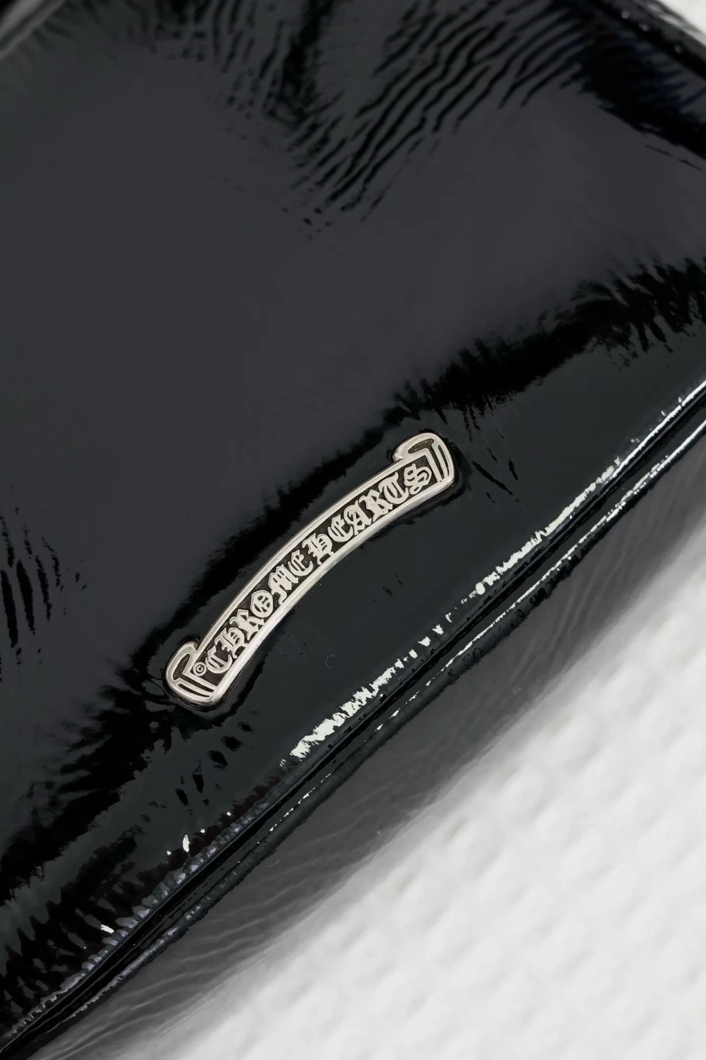 Крупный план серебряной плашки с гравировкой Chrome Hearts на тыльной стороне