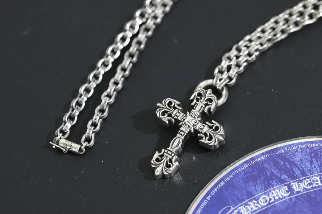 Сложенная цепочка рядом с резной подвеской-крестом Chrome Hearts