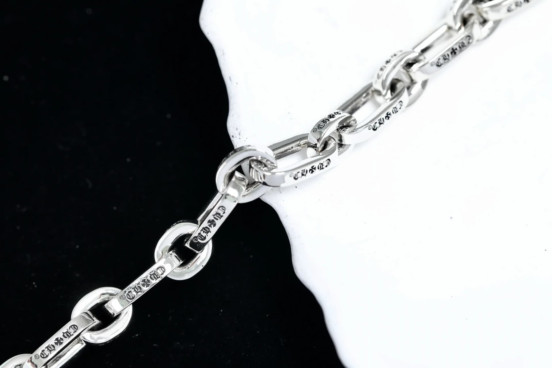 Крупный план звеньев серебряного браслета Chrome Hearts с фирменной гравировкой