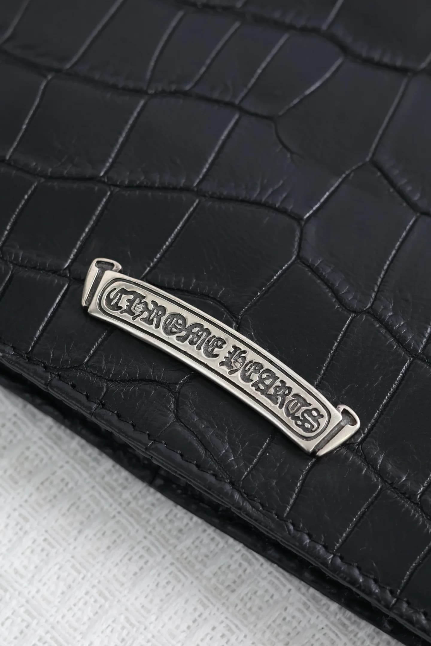 Серебряный свиток с гравировкой Chrome Hearts на фактурной коже крупным планом