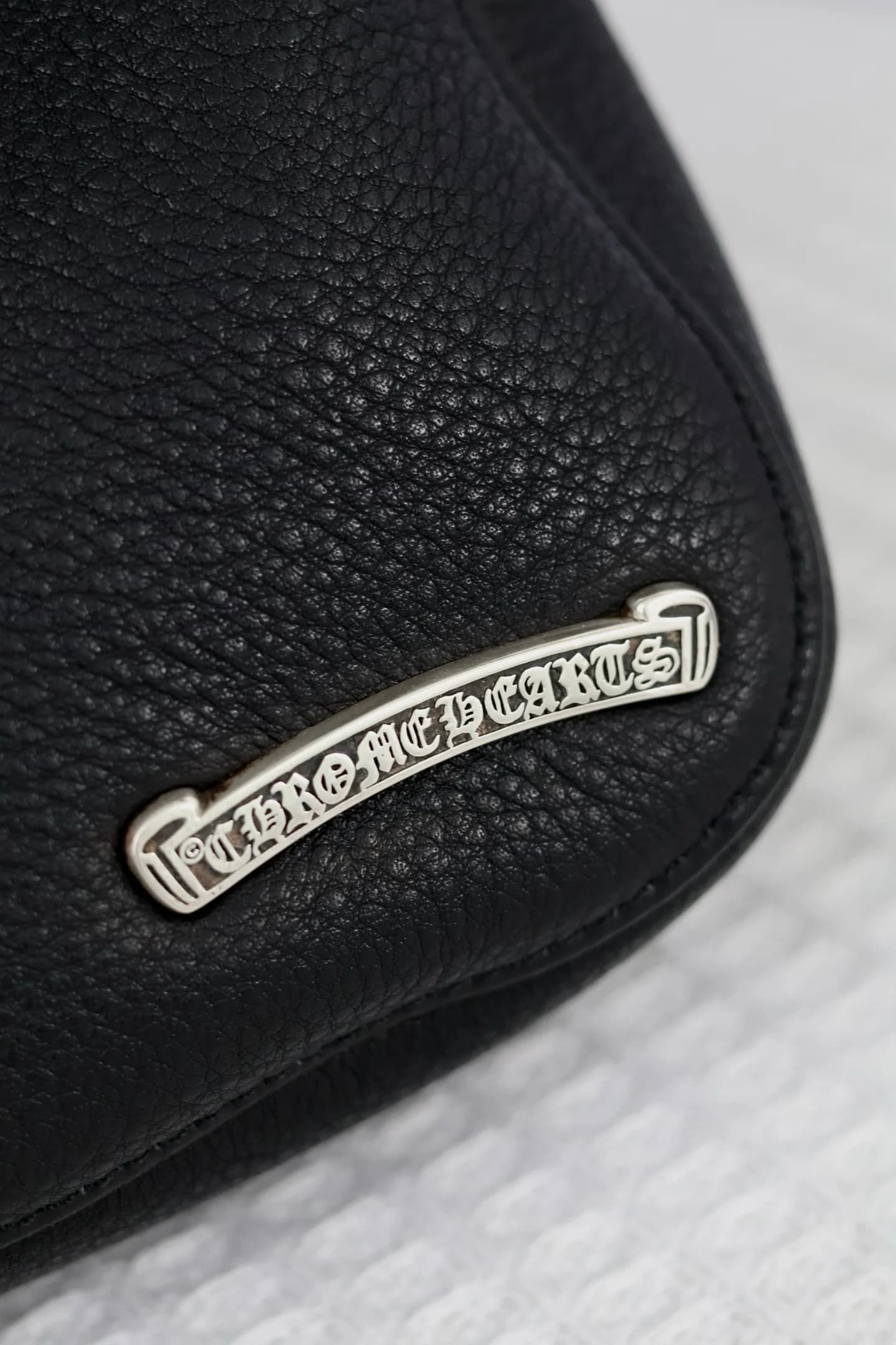 Крупный план серебряной плашки с фирменным логотипом Chrome Hearts