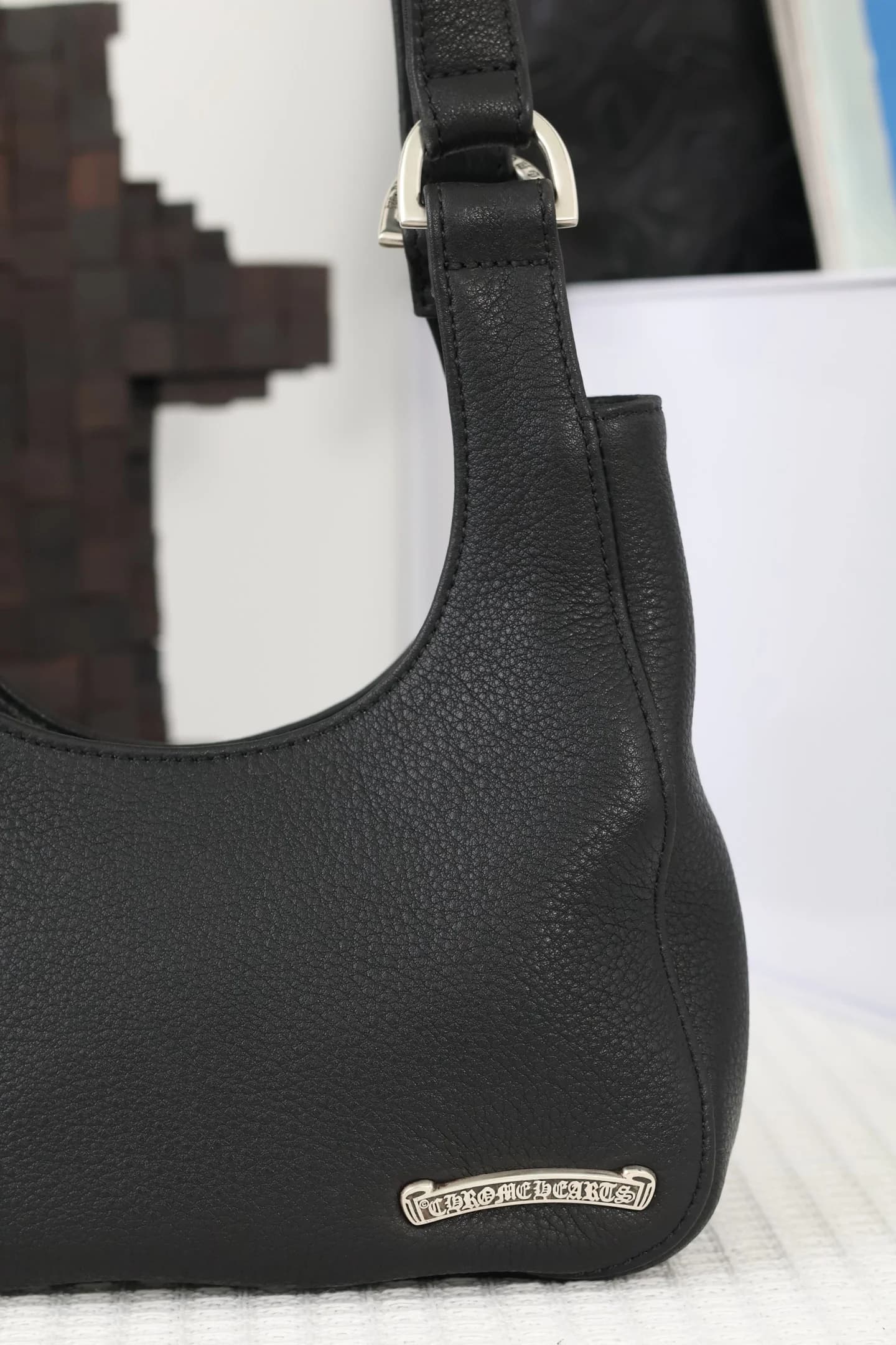 Металлическая плашка с логотипом Chrome Hearts на кожаном корпусе