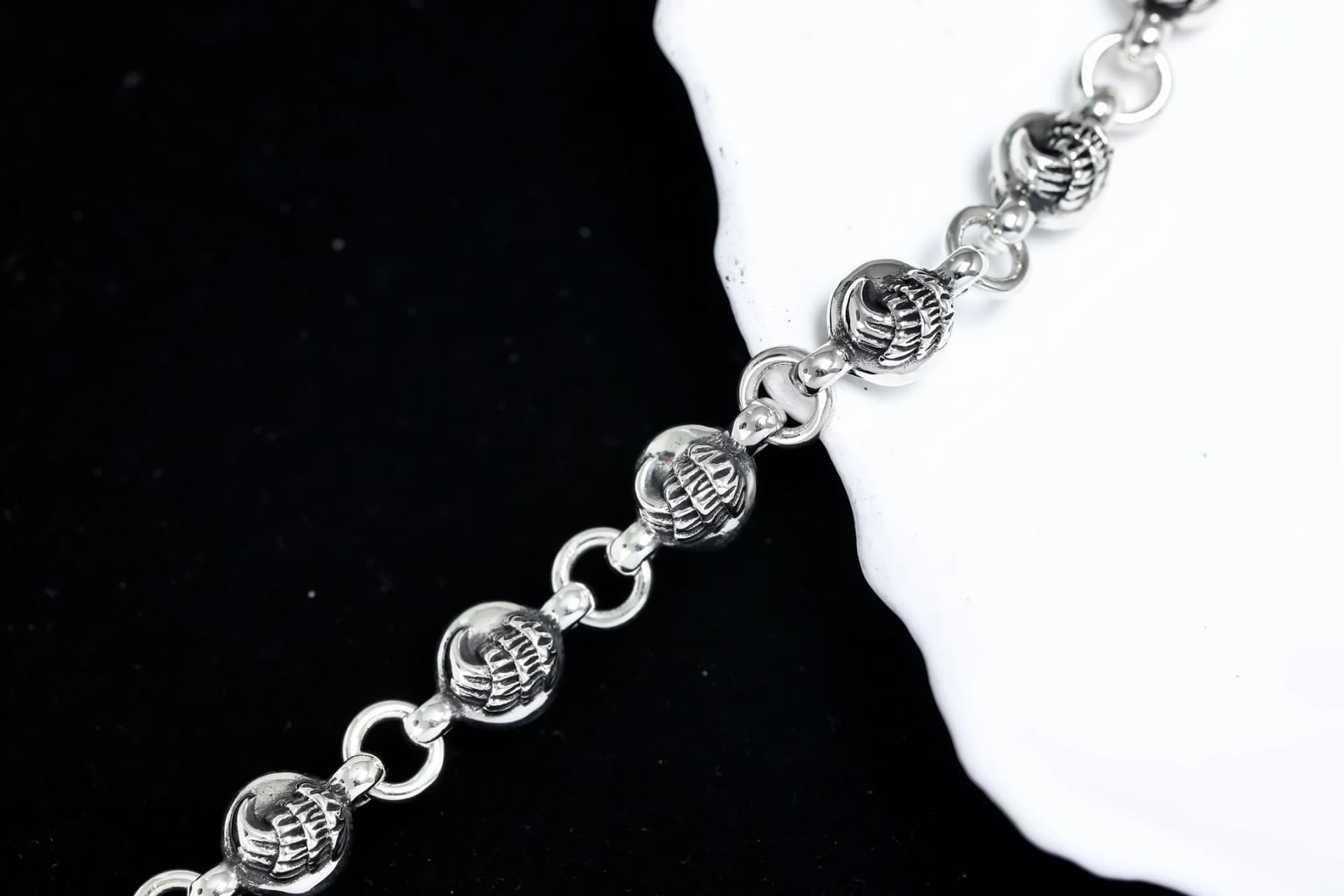Крупный план звеньев и рельефных элементов серебряного браслета Chrome Hearts