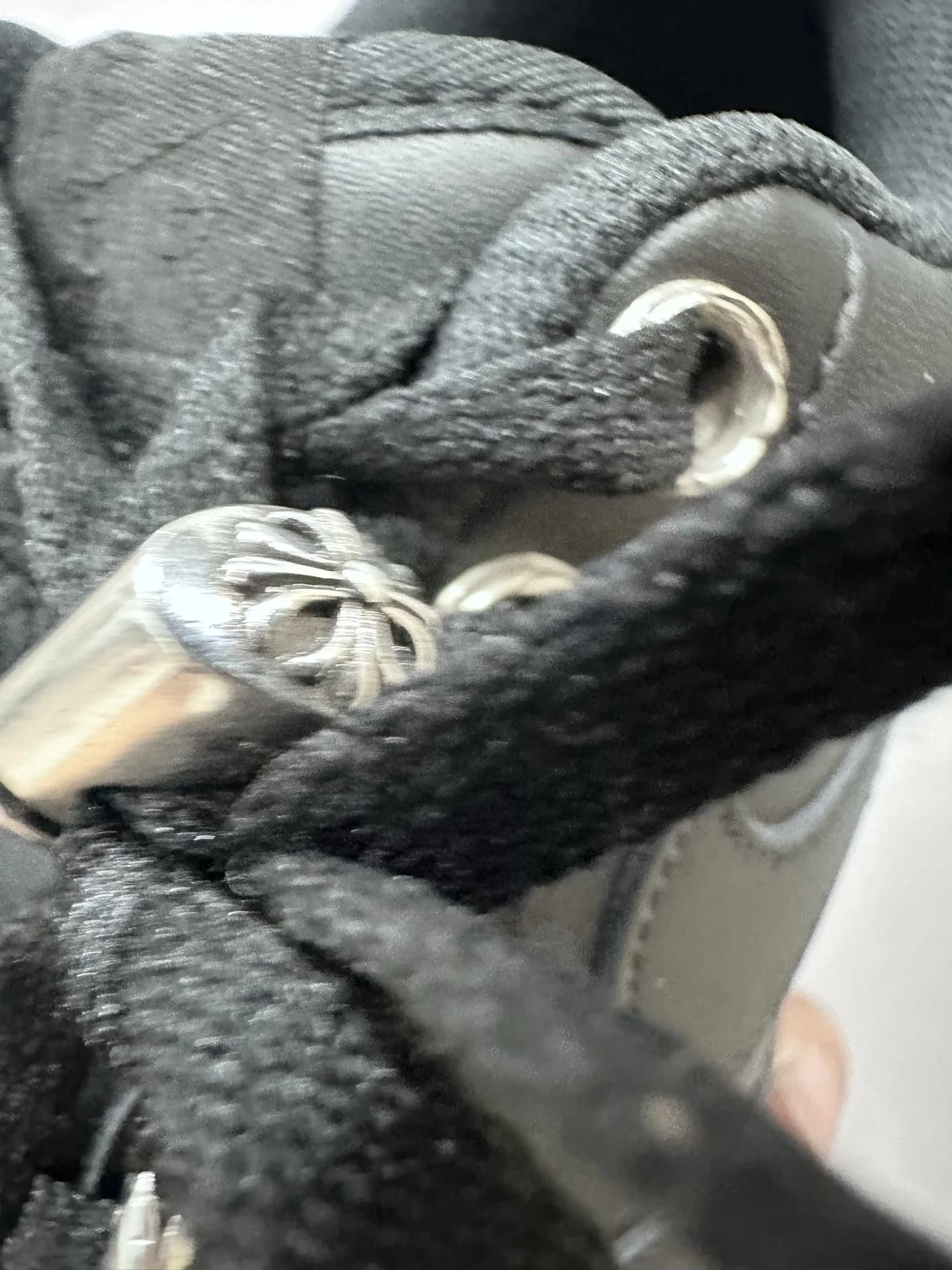 Крупный план серебряного элемента на шнурках Chrome Hearts