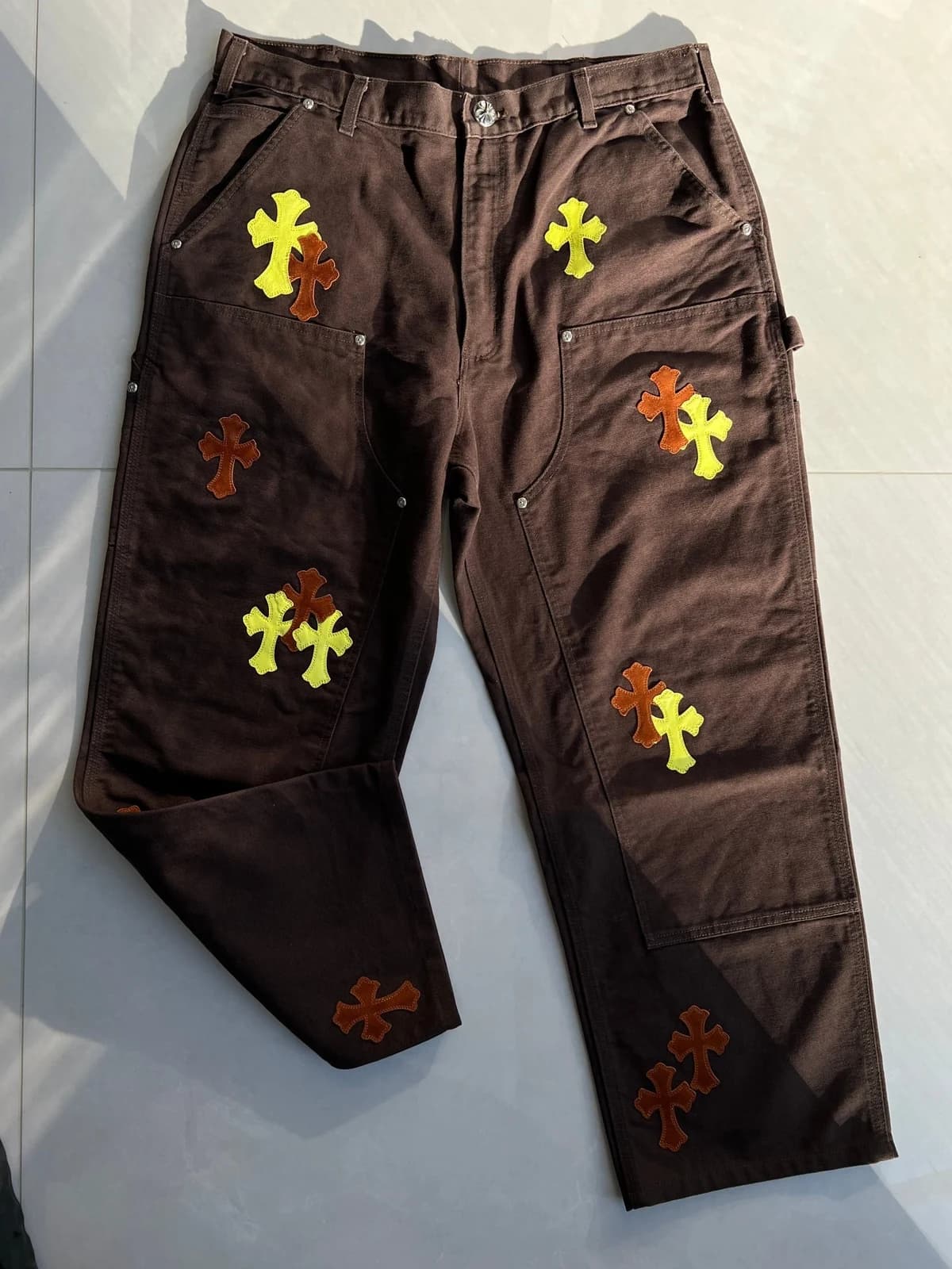 Коричневые брюки-карпентер Chrome Hearts с заклёпками и кожаными крестами, вид под углом