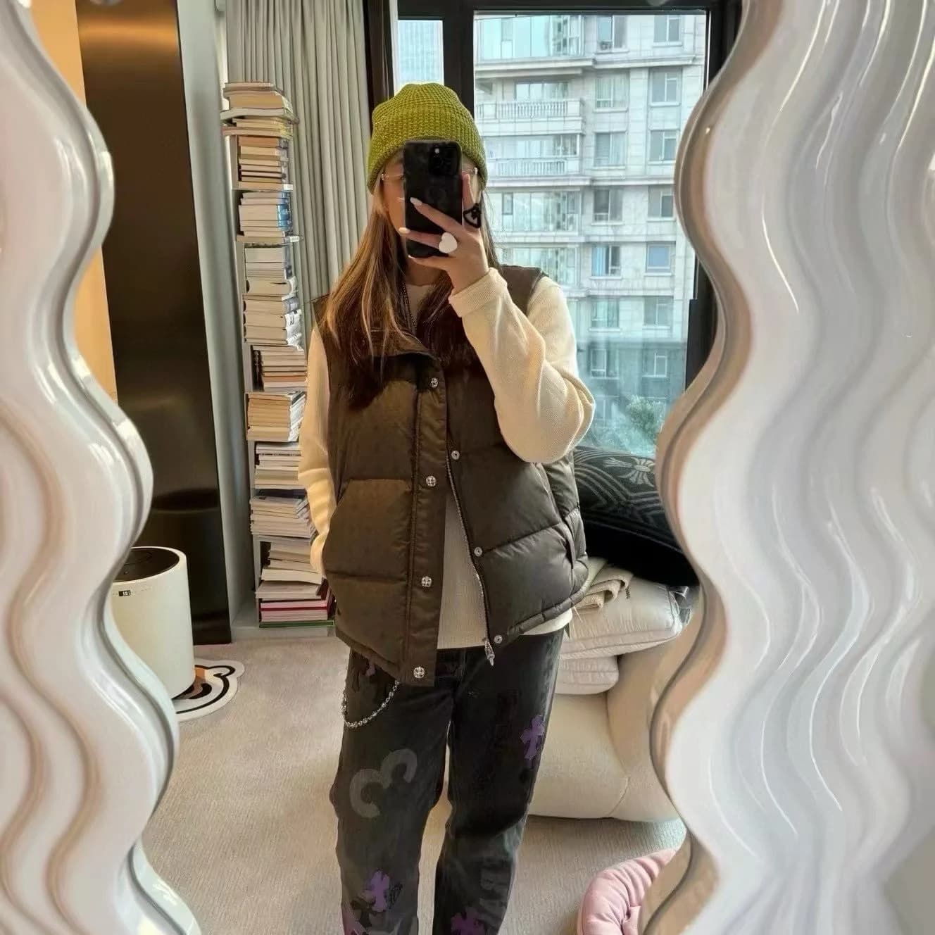 Девушка в оливковом пуховом жилете Chrome Hearts у зеркала