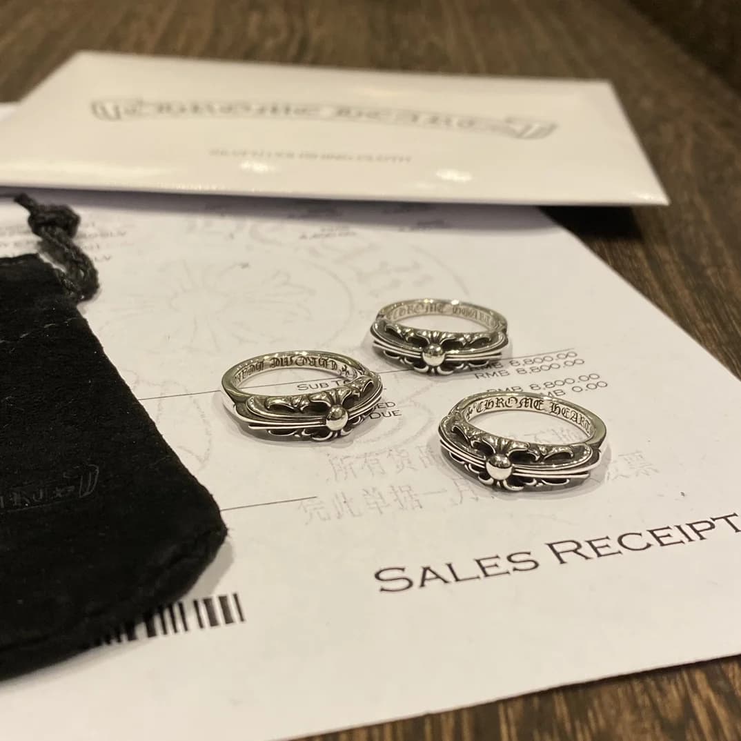 Серебряные кольца Chrome Hearts на фирменном чеке рядом с замшевым пыльником