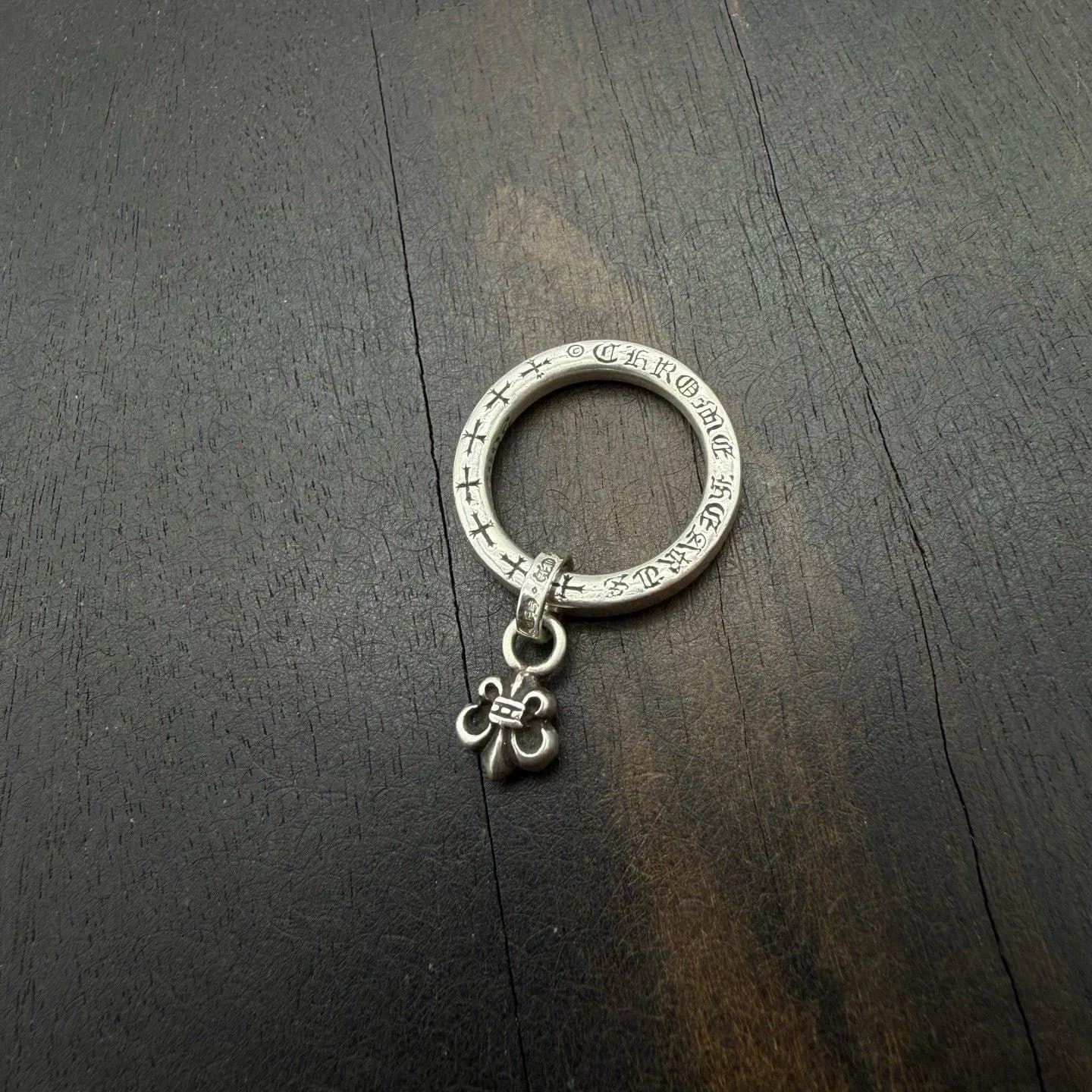 Серебряное кольцо Chrome Hearts с подвеской в виде лилии BS Fleur на деревянном фоне