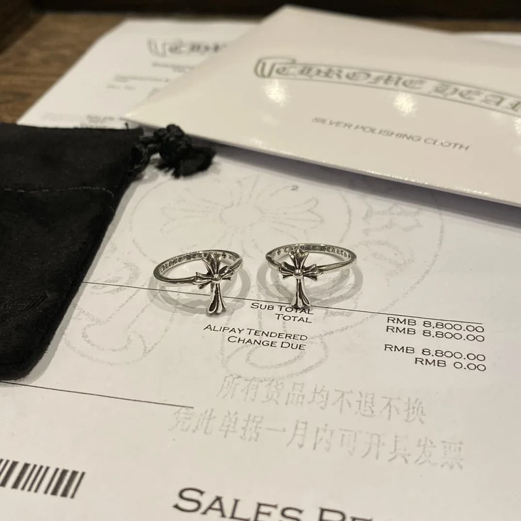 Серебряные кольца Chrome Hearts на чеке рядом с чехлом и салфеткой