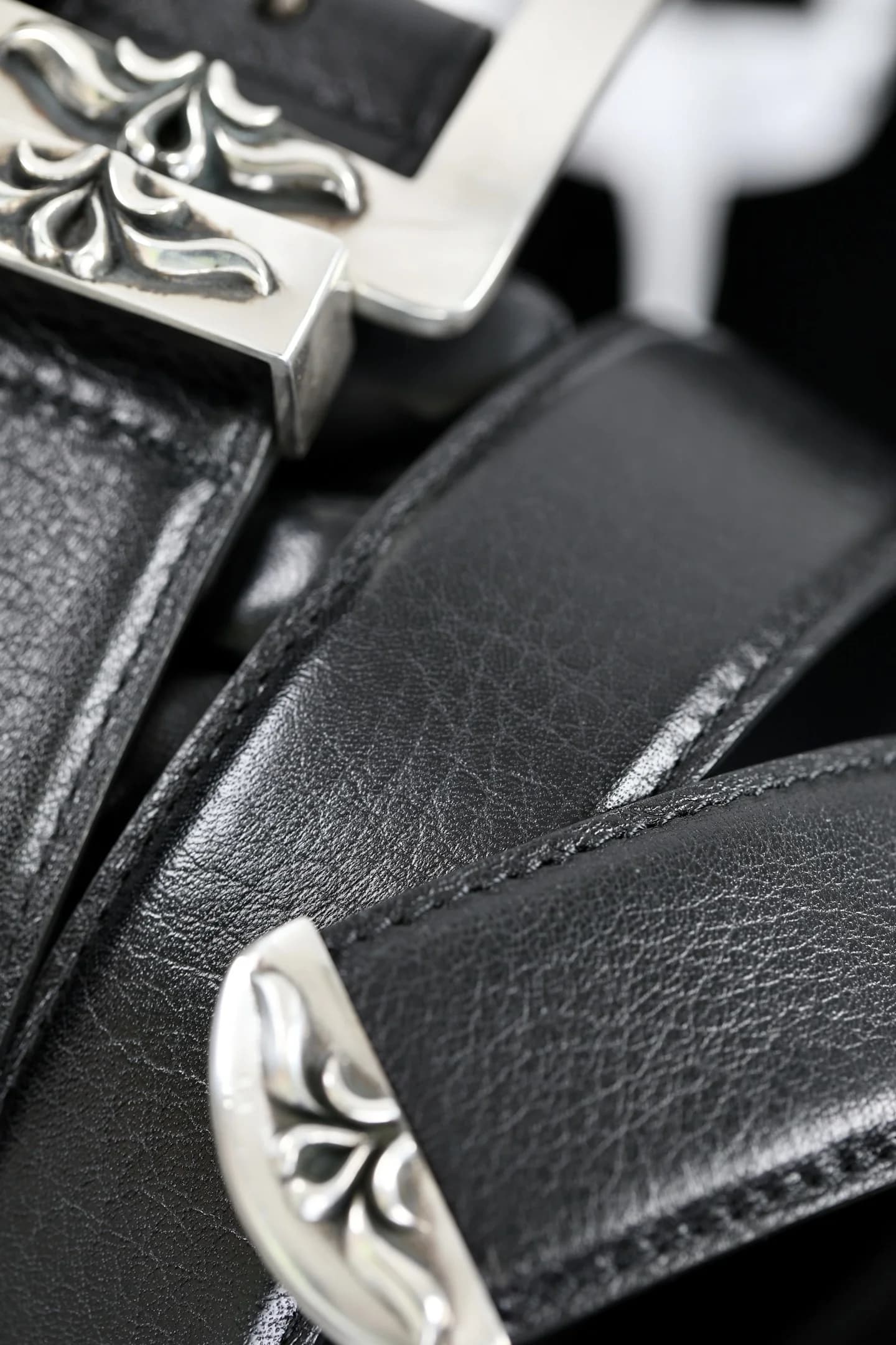 Фактура натуральной кожи ремня Chrome Hearts и серебряные декоративные элементы крупным планом