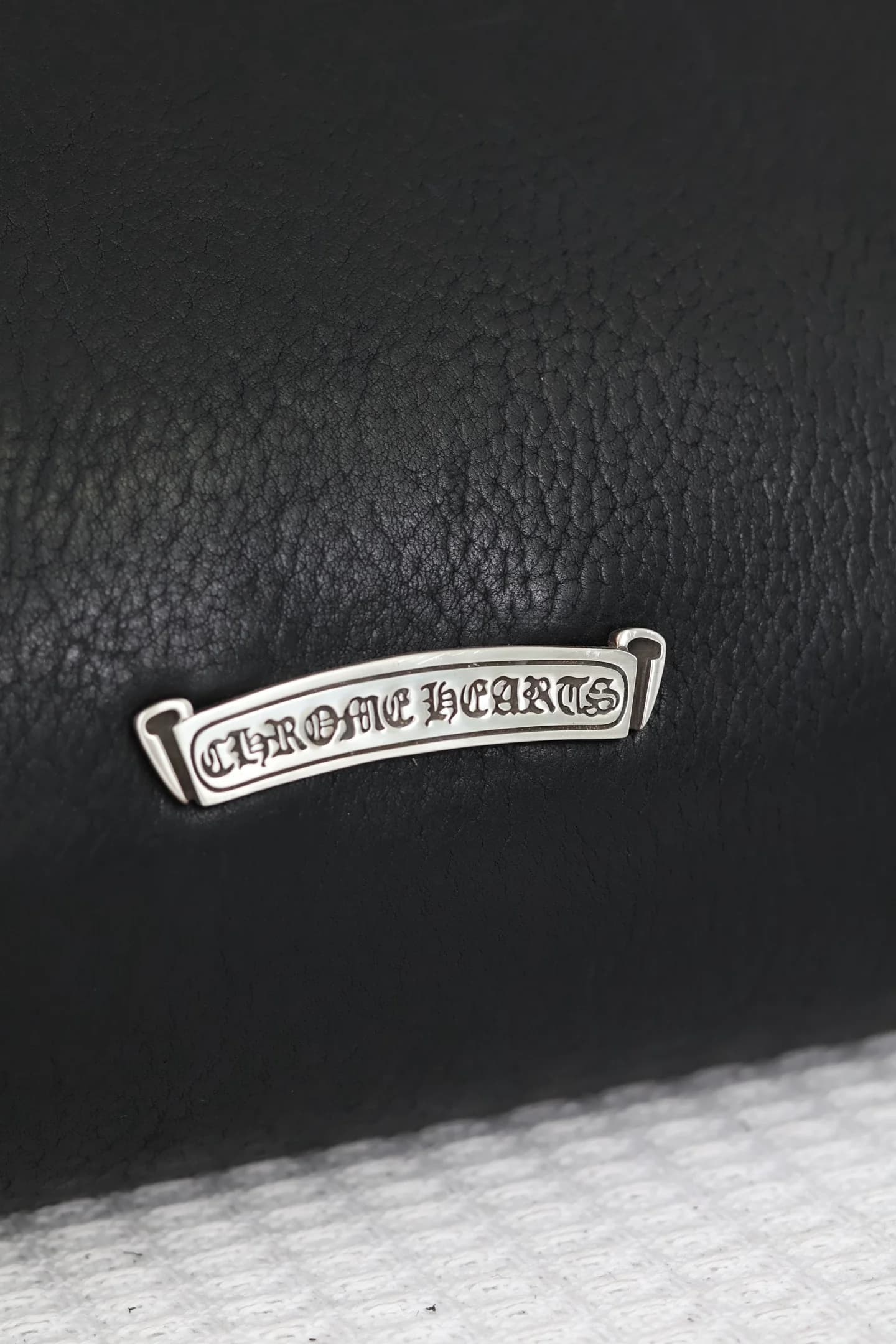 Серебряная плашка с гравировкой Chrome Hearts крупным планом