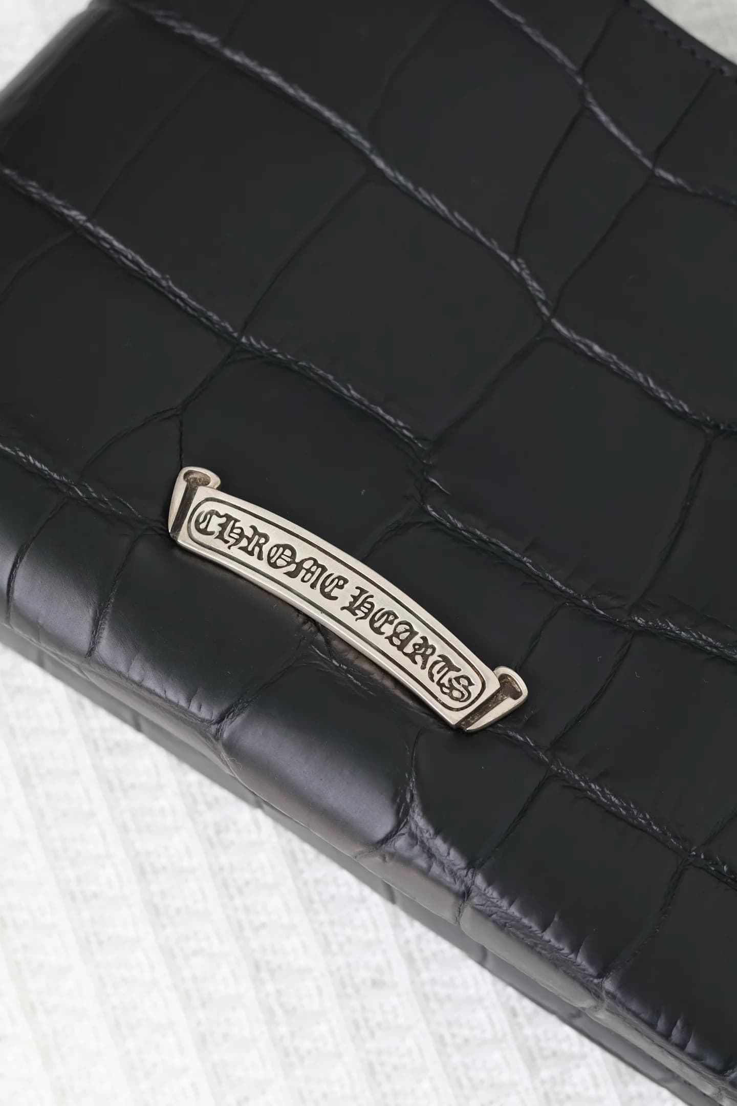 Крупный план серебряной плашки с гравировкой Chrome Hearts на обратной стороне