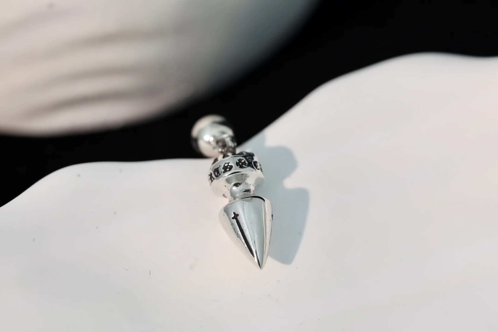 Крупный план конусовидной подвески серьги Chrome Hearts с чернением и гравировкой