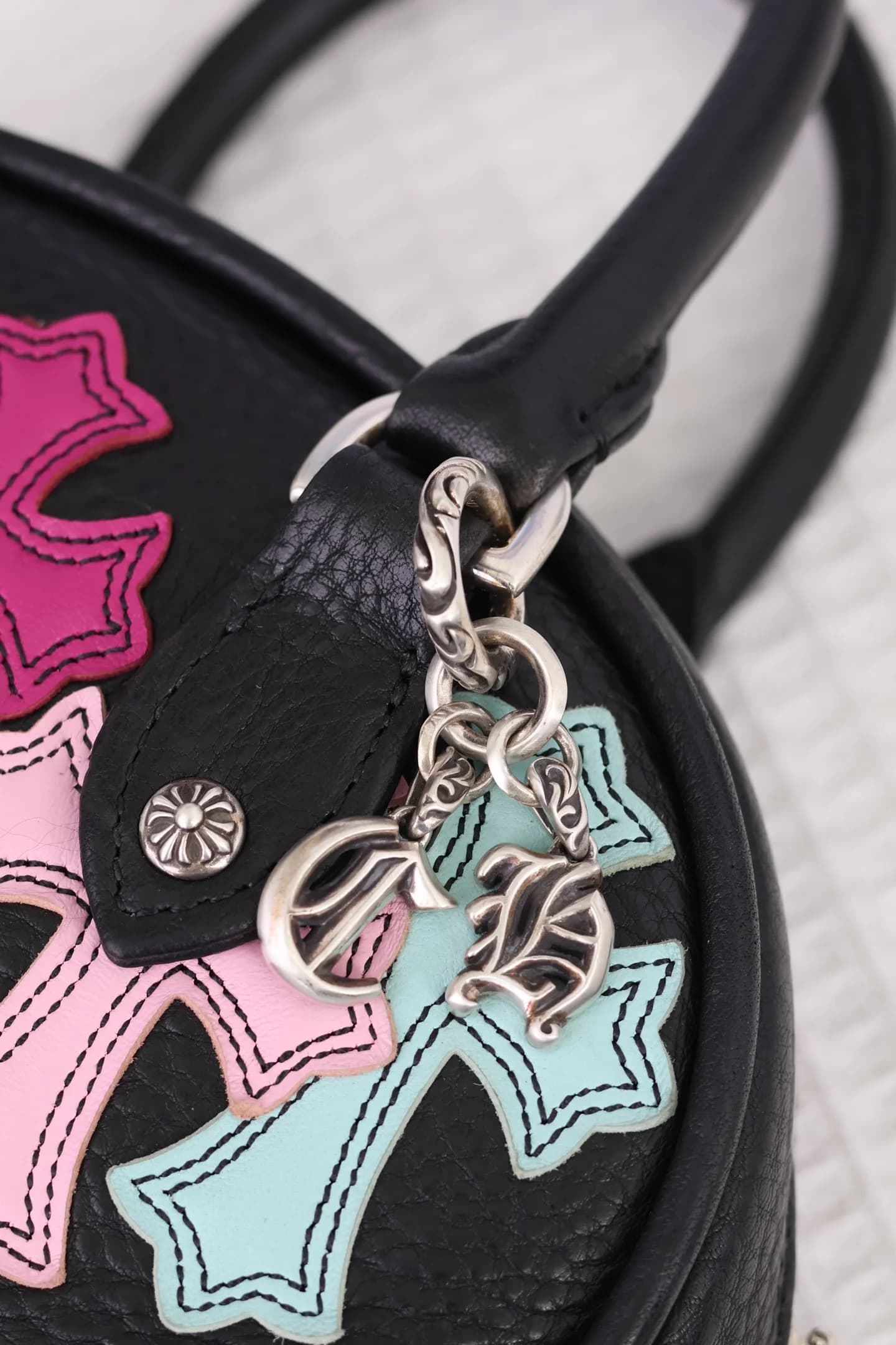 Крупный план серебряных шармов на ручке сумки Chrome Hearts