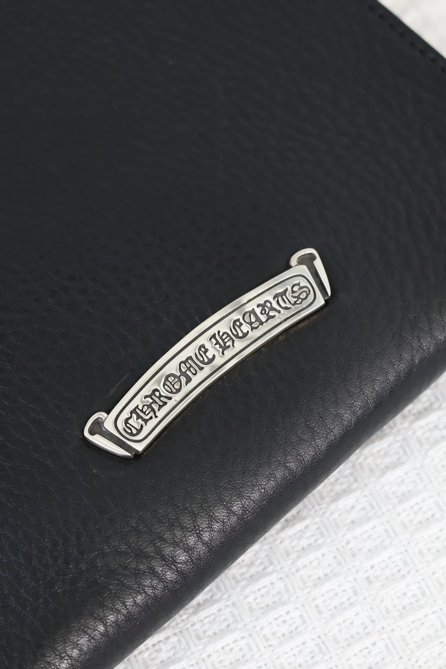 Серебряная фигурная плашка с гравировкой бренда Chrome Hearts крупным планом