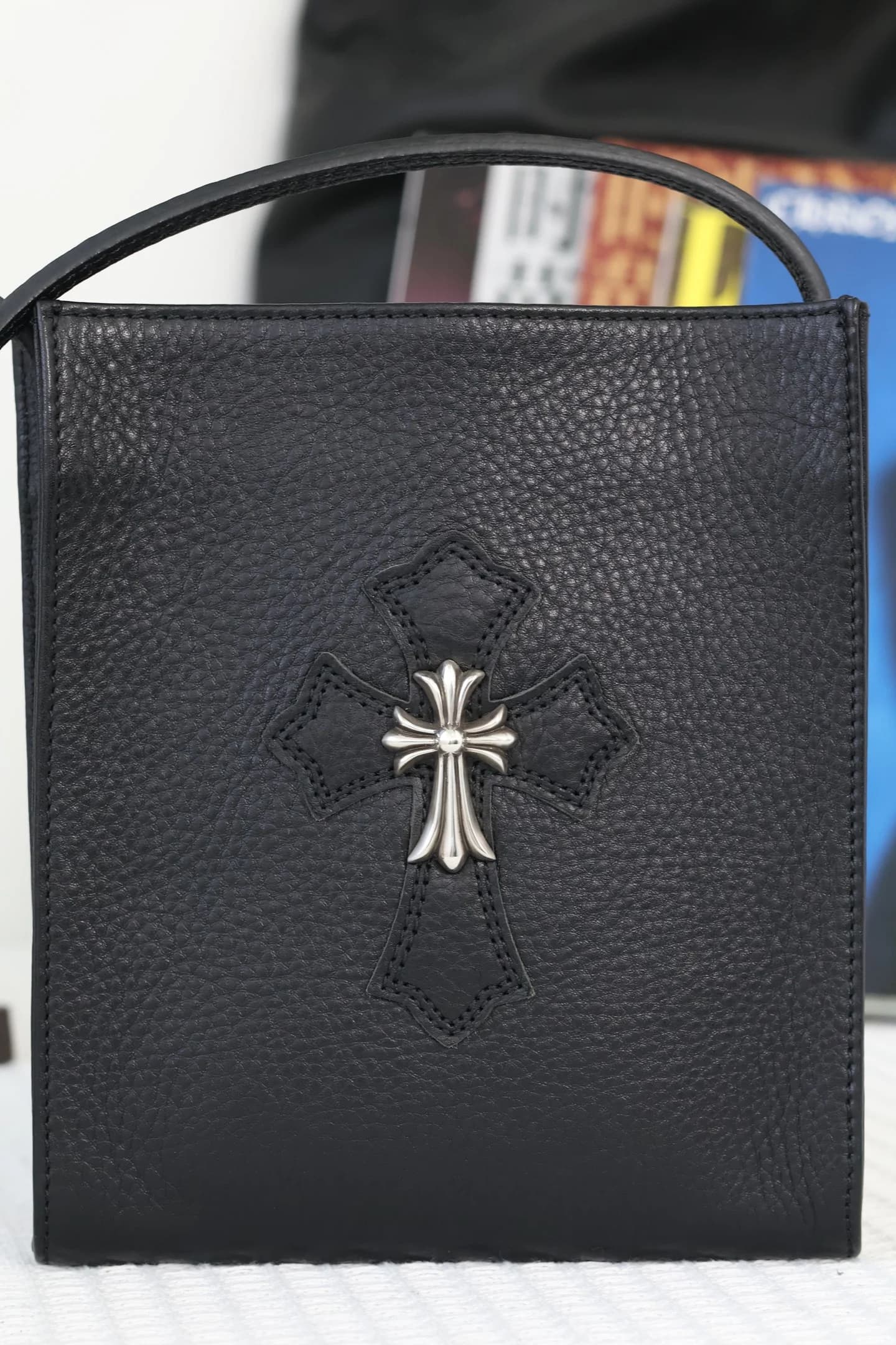 Крупный план лицевой стороны сумки Chrome Hearts с кожаным крестом и серебряной деталью