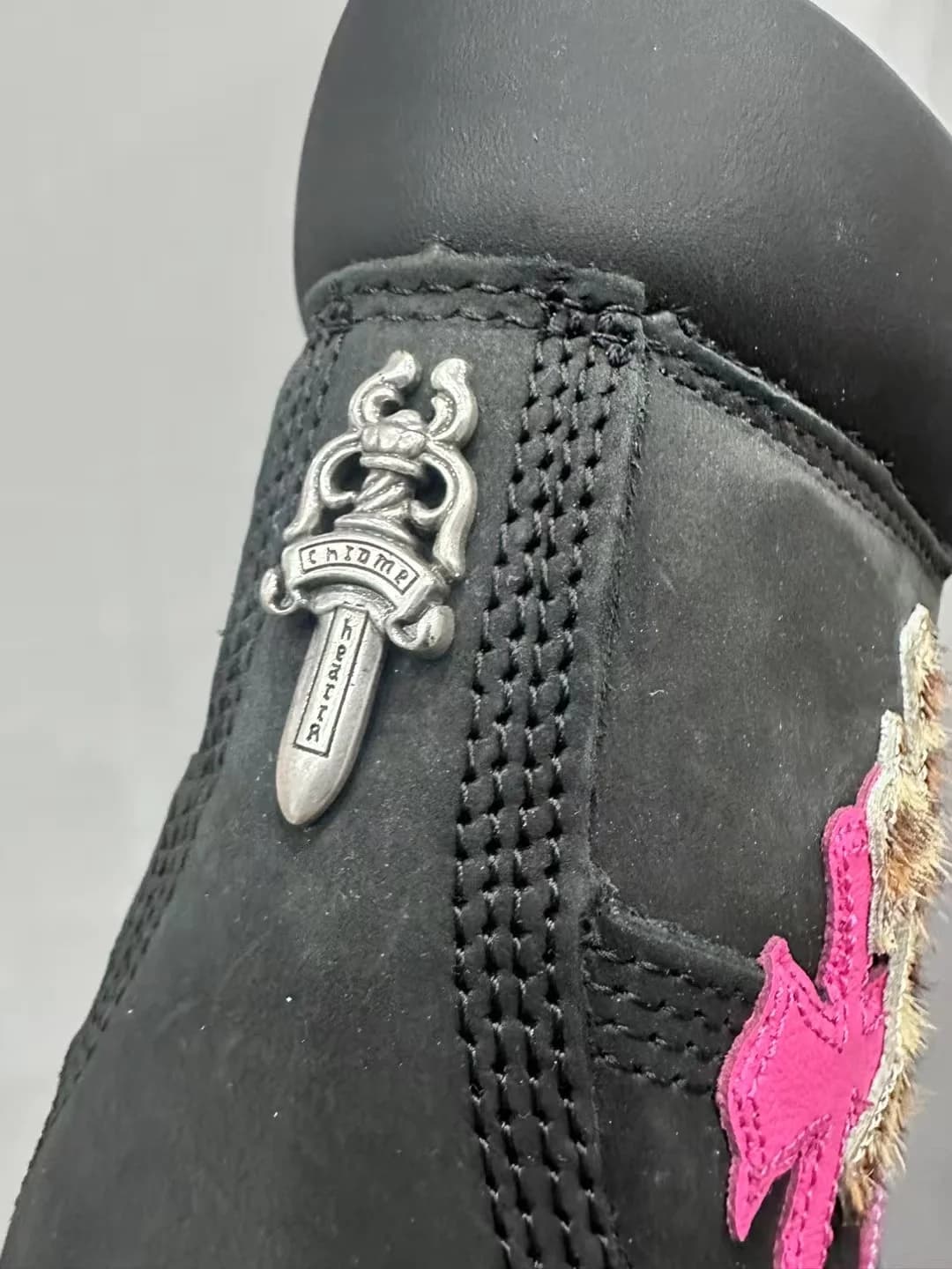 Крупный план серебряной подвески-кинжала на заднике ботинка Chrome Hearts