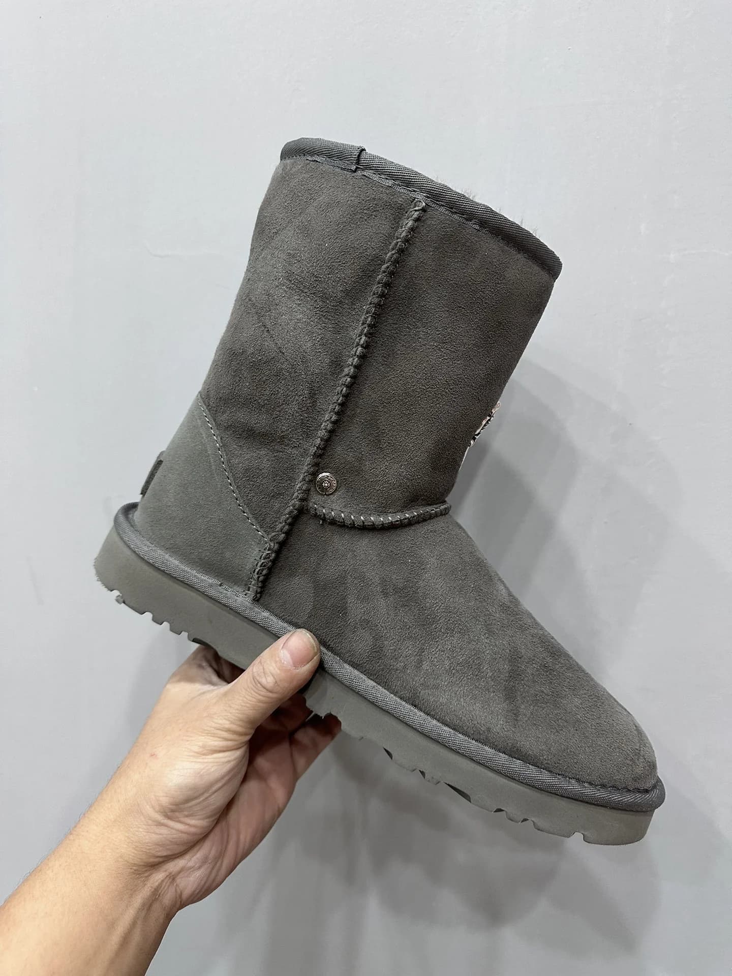 Серые замшевые сапоги-угги Chrome Hearts x UGG в руке, вид сбоку