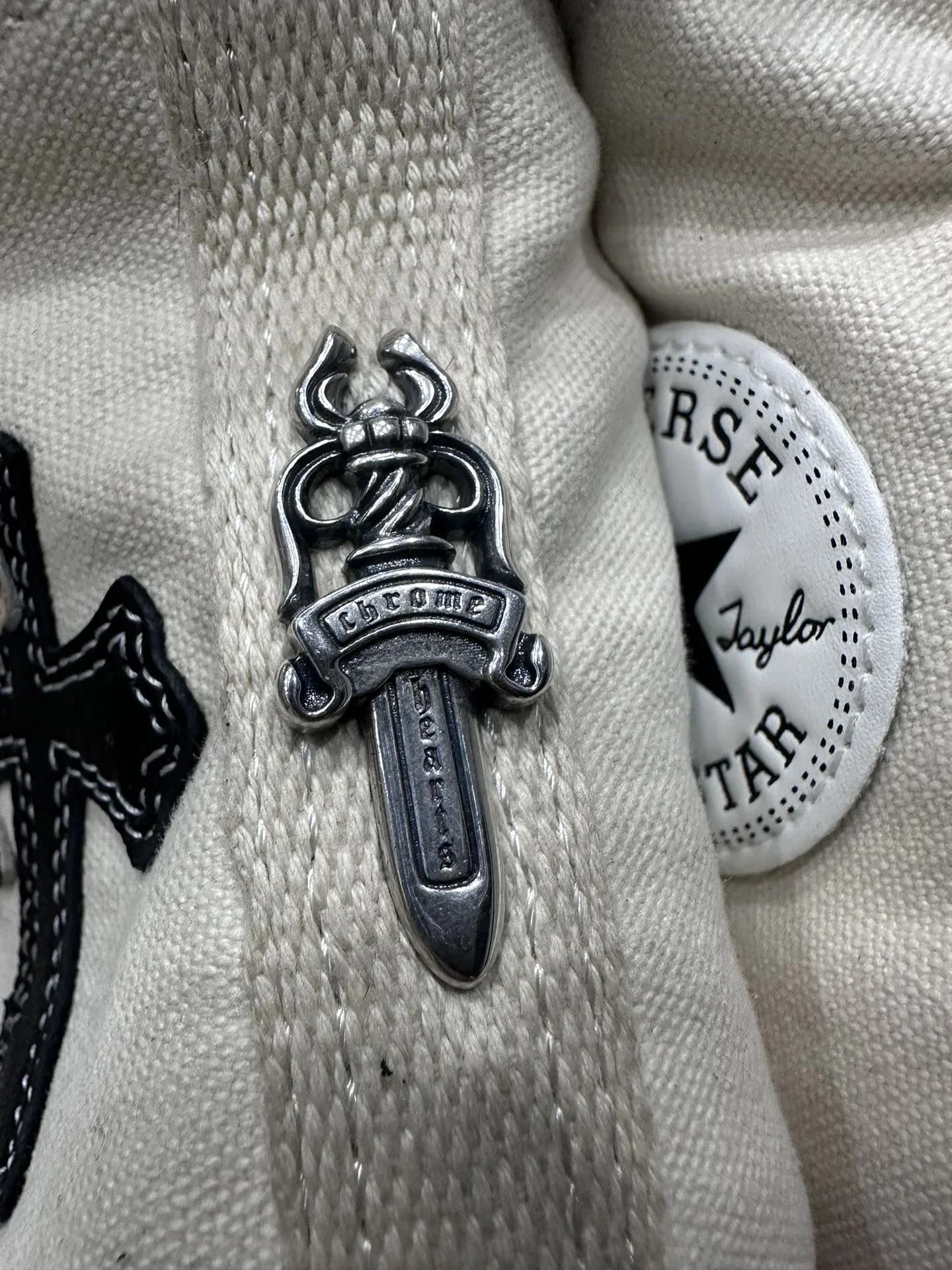 Крупный план серебряной детали в виде кинжала на заднике кед Chrome Hearts x Converse Chuck 70