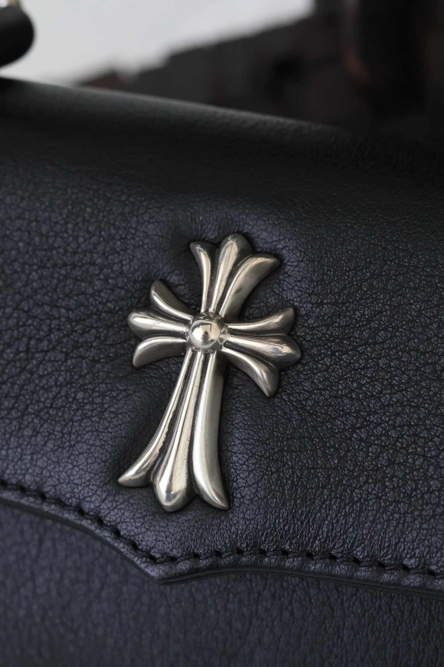 Крупный план серебряного креста 925 пробы на клапане сумки Chrome Hearts