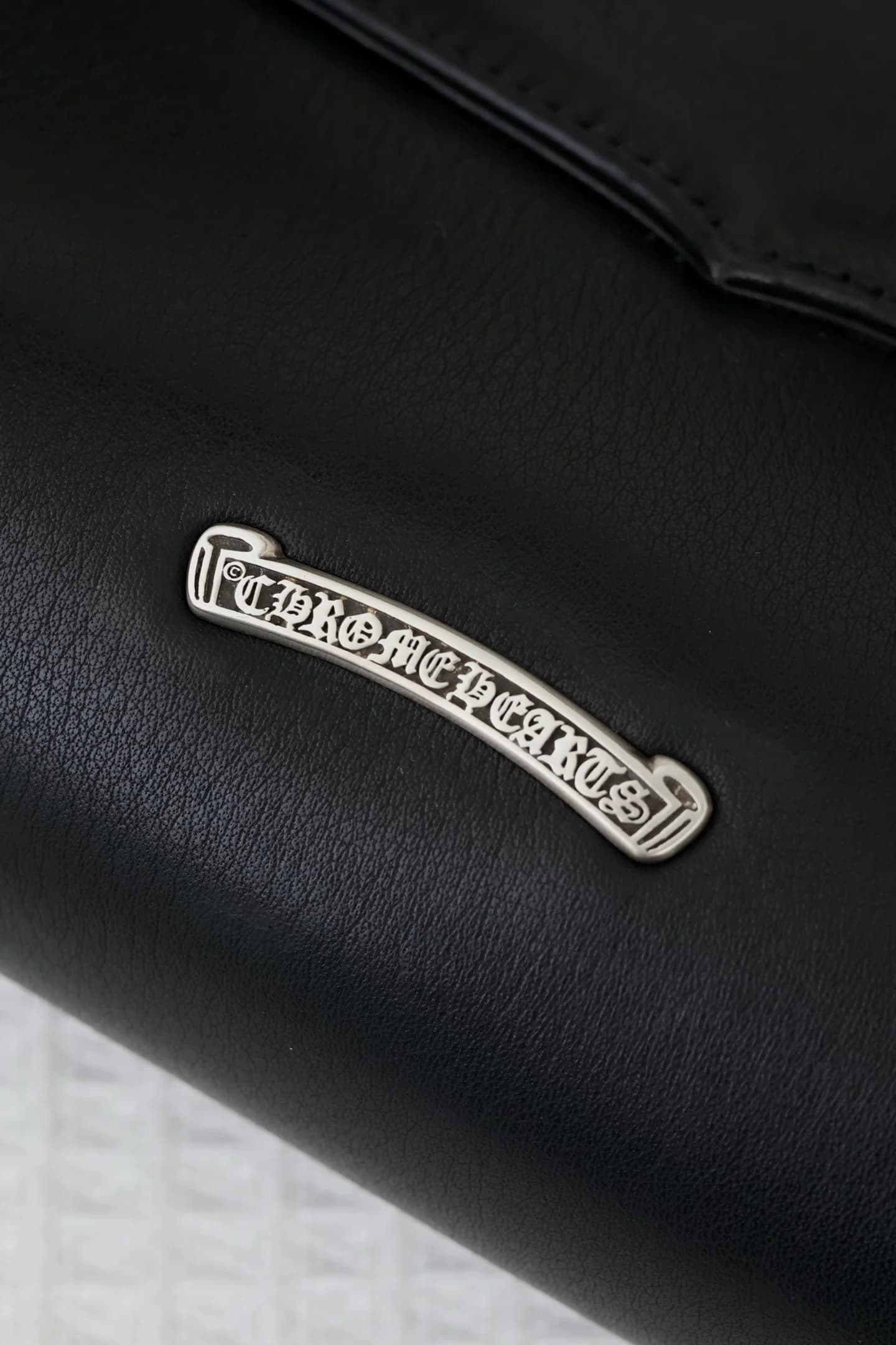 Крупный план серебряной плашки с логотипом Chrome Hearts на задней панели