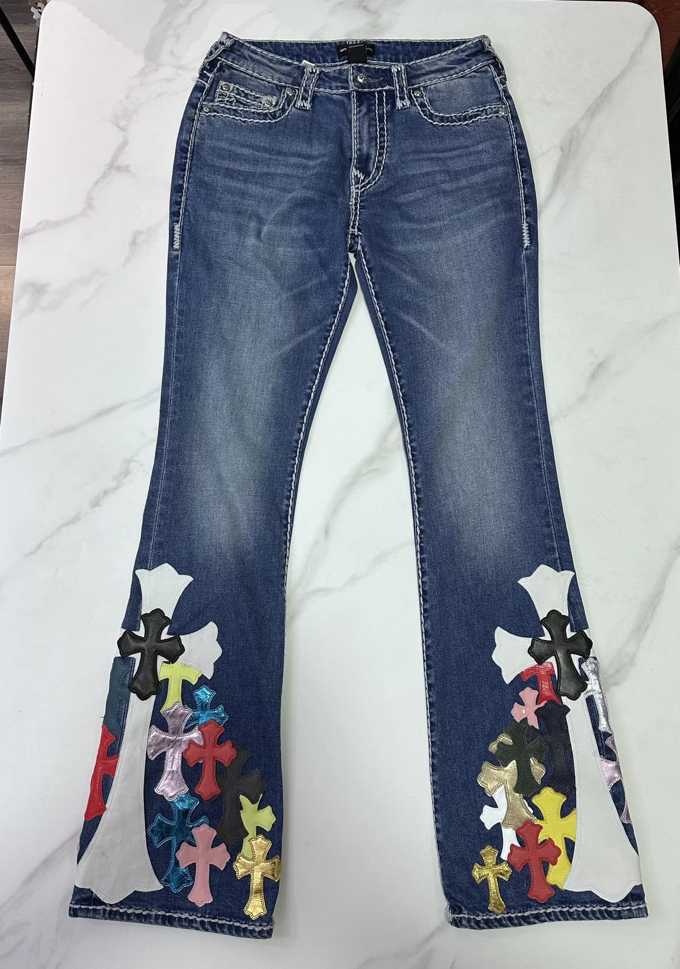 Синие расклешенные джинсы Chrome Hearts с разноцветными кожаными нашивками-крестами, вид спереди