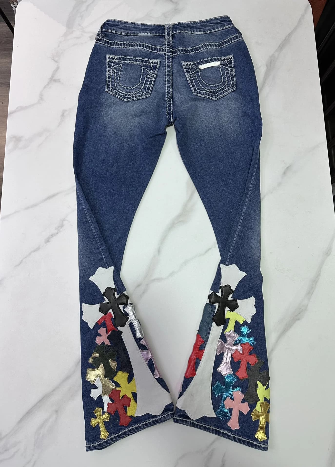 Синие расклешенные джинсы Chrome Hearts сзади с разведенными штанинами