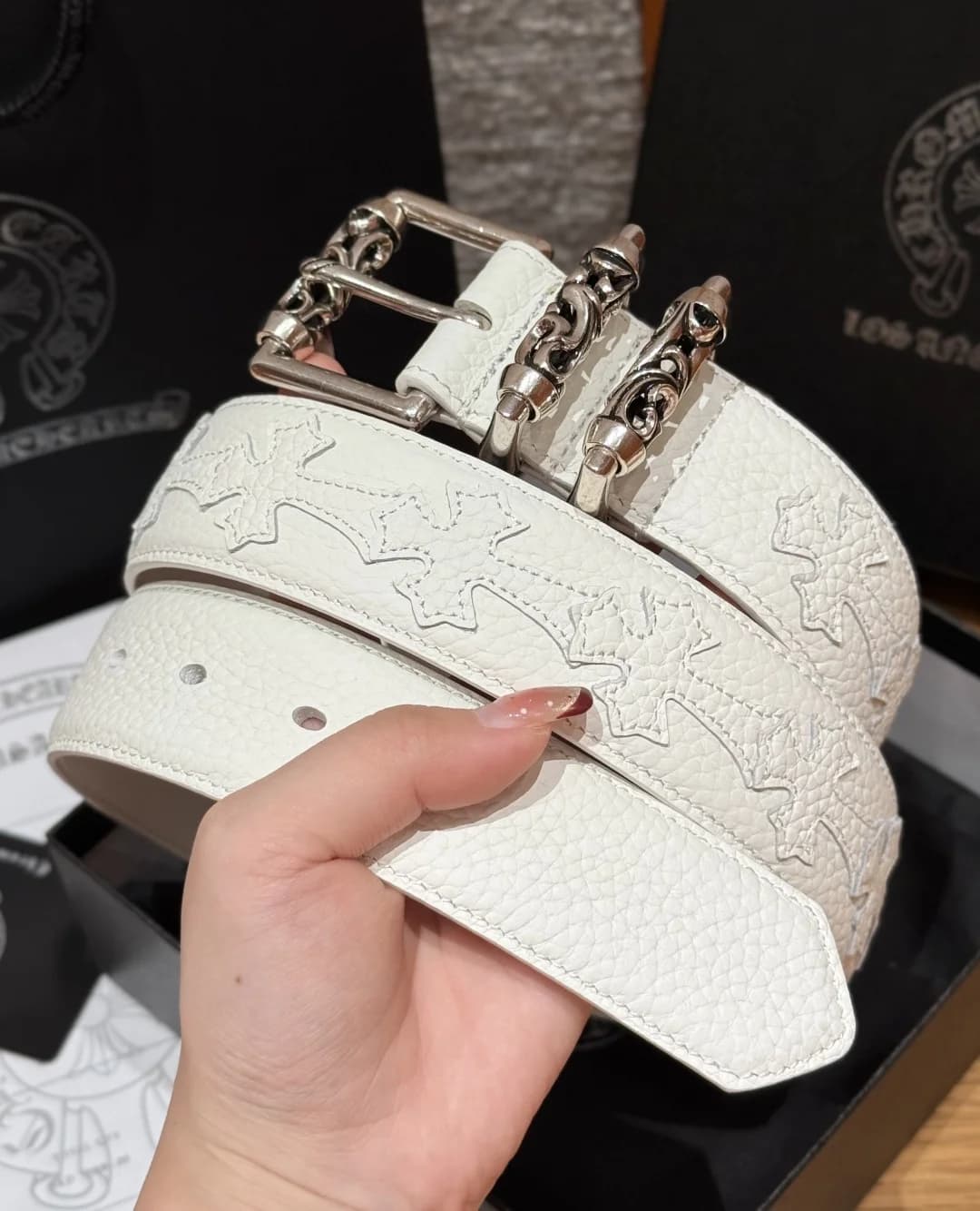 Белый ремень Chrome Hearts с декоративным узором крестов в руке