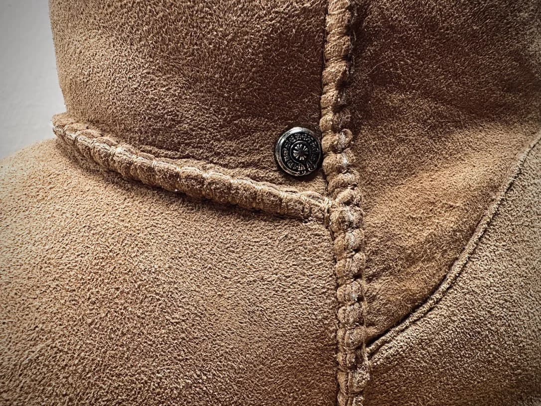 Деталь шва и серебряная заклепка-крест Chrome Hearts на сапогах UGG
