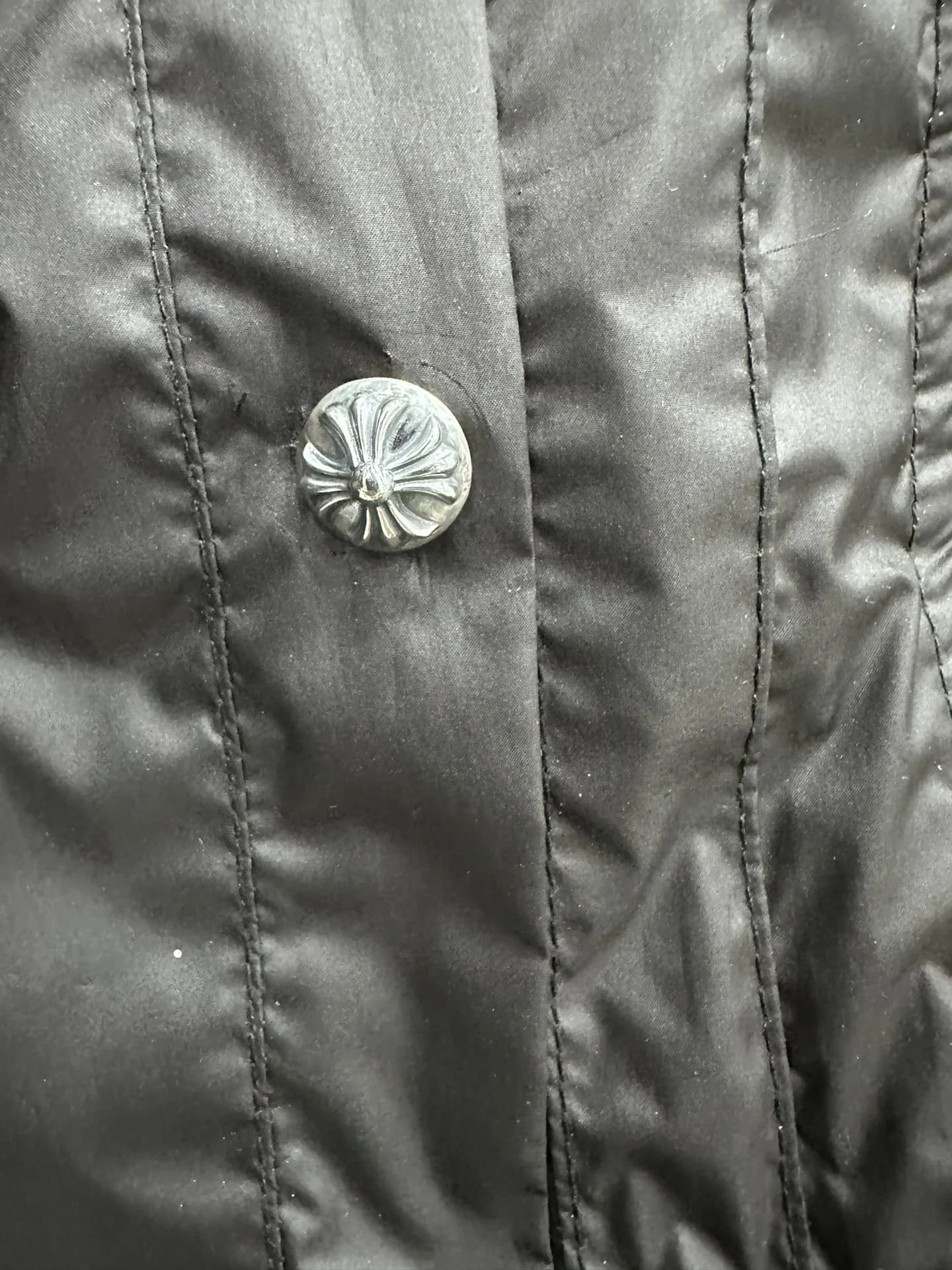 Деталь пуховика Chrome Hearts: серебряная кнопка с гравировкой
