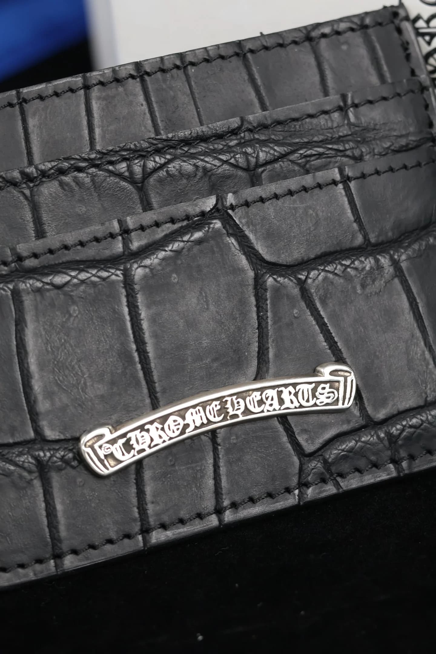 Крупный план серебряной плашки с гравировкой Chrome Hearts на фактурной коже