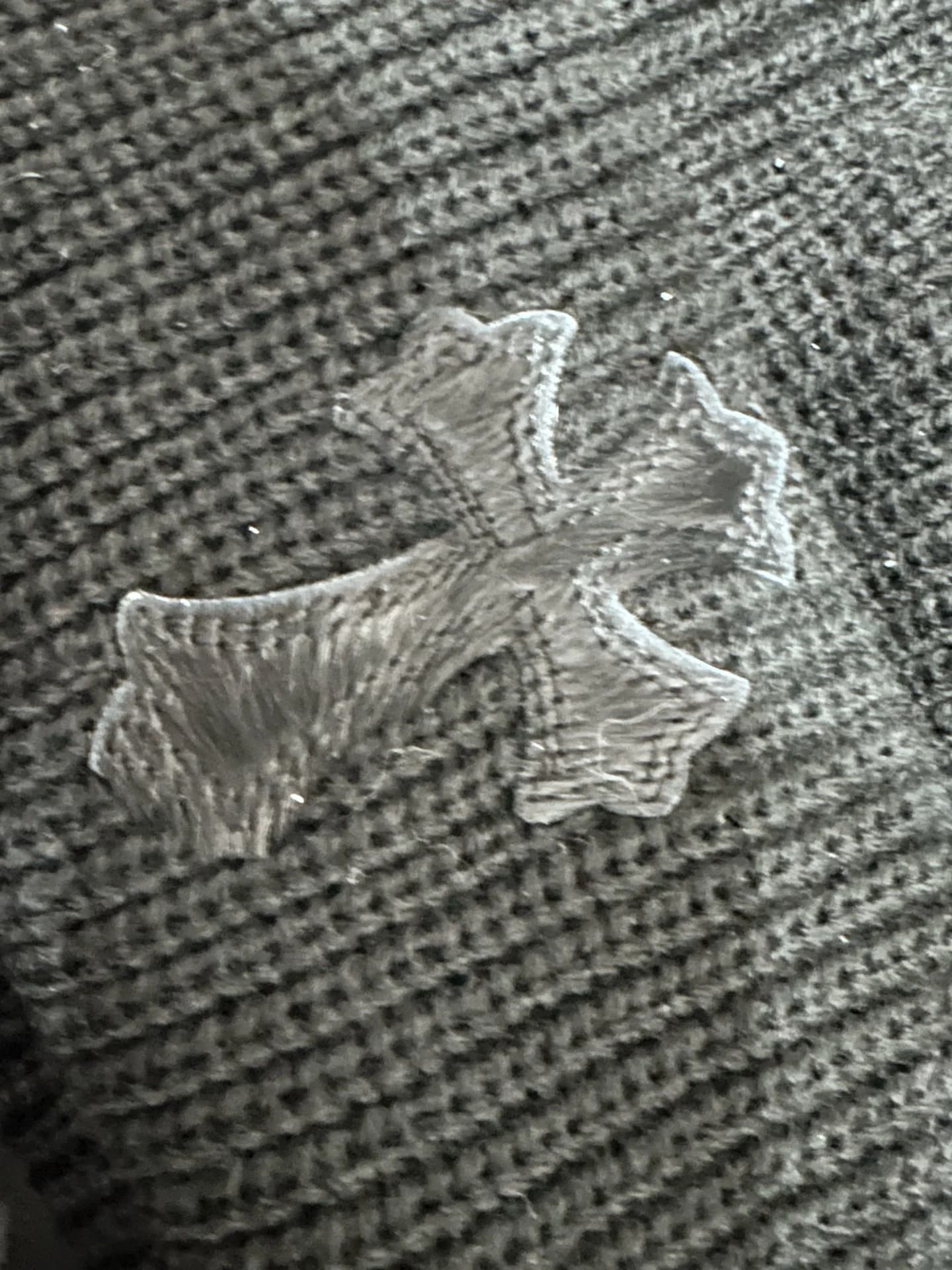 Деталь нашивки в виде креста на черной вязаной шапке Chrome Hearts