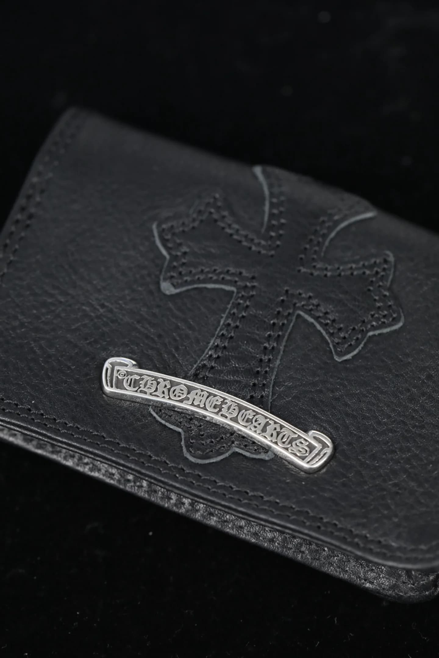 Крупный план серебряной плашки скролла и кожаной нашивки в виде креста Chrome Hearts