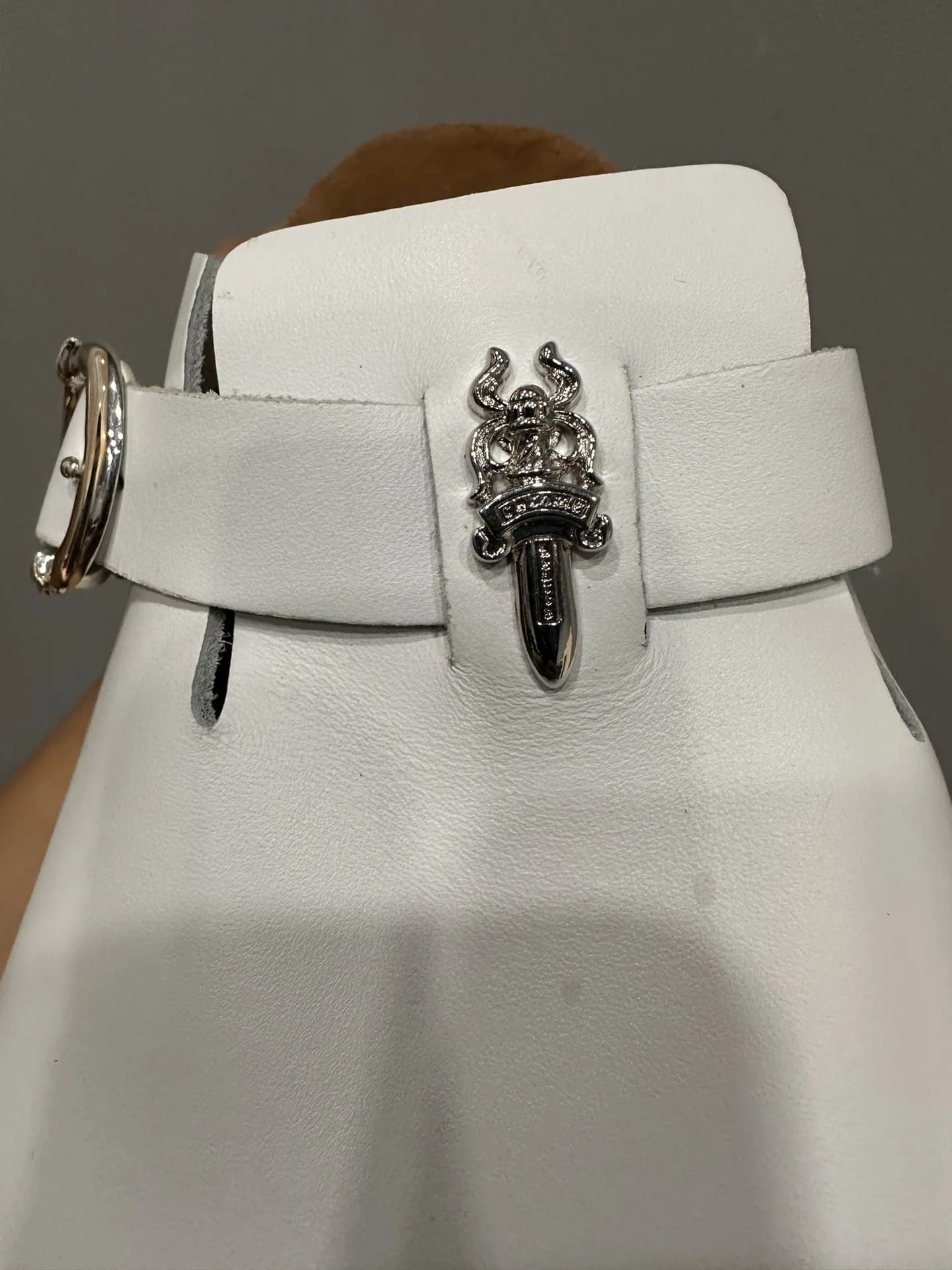 Деталь ремешка белых сабо Chrome Hearts с серебряным кинжалом