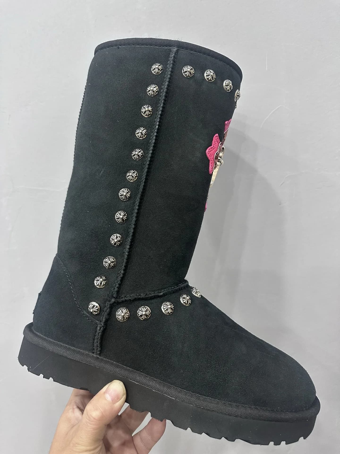 Вид сбоку на высокие черные угги Chrome Hearts x UGG Classic с металлическими заклепками